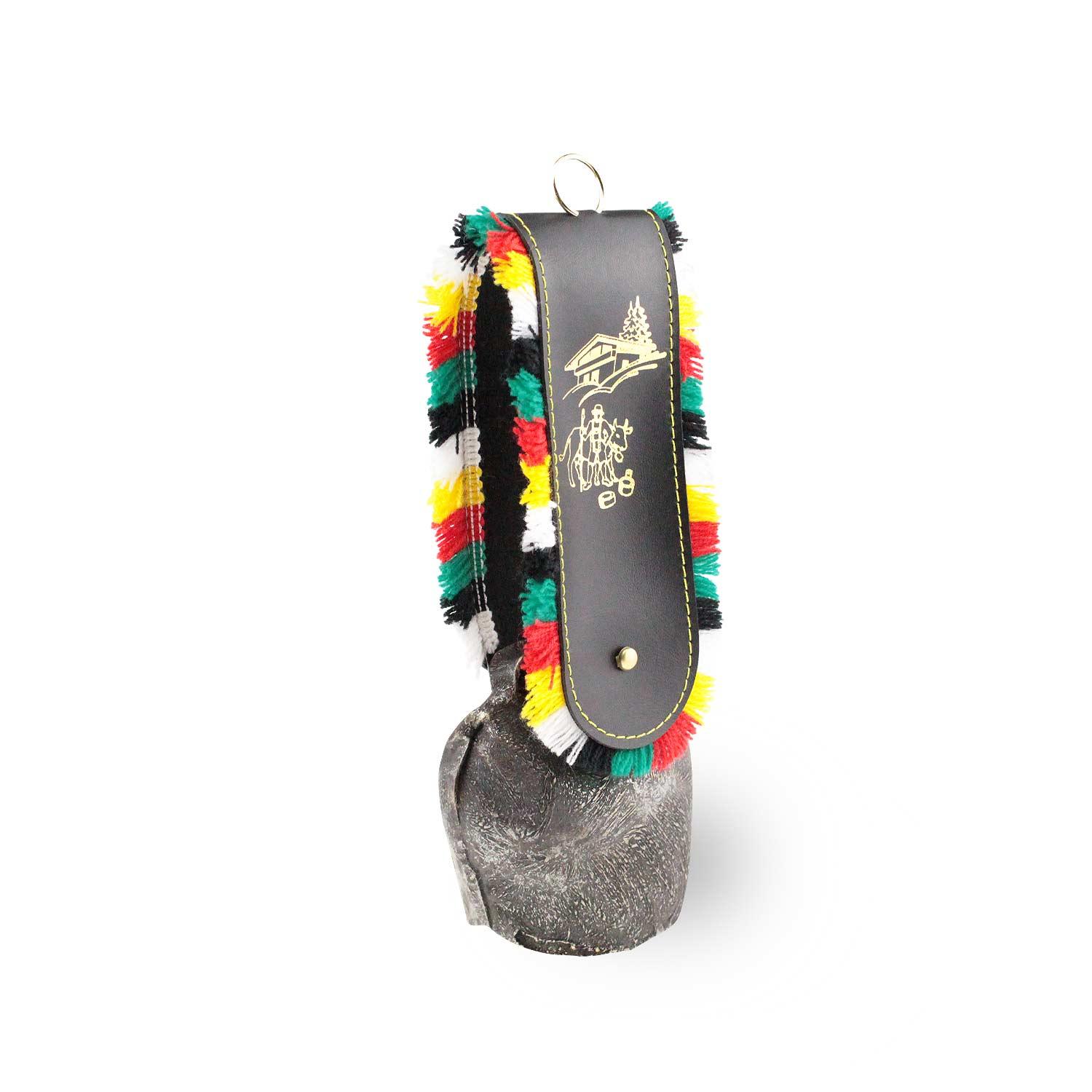 Rustikale Kuhglocke mit aufwendig verziertem schwarzem Ledergurt und bunten Quasten, traditionelles Alpenaccessoire.