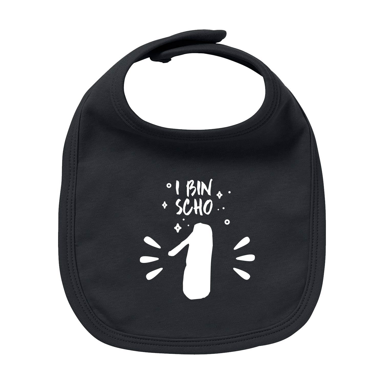 Weißes Baby-Lätzchen mit blauem Aufdruck „I bin scho 1!“, runder Halsausschnitt, aus Bio-Baumwolle.