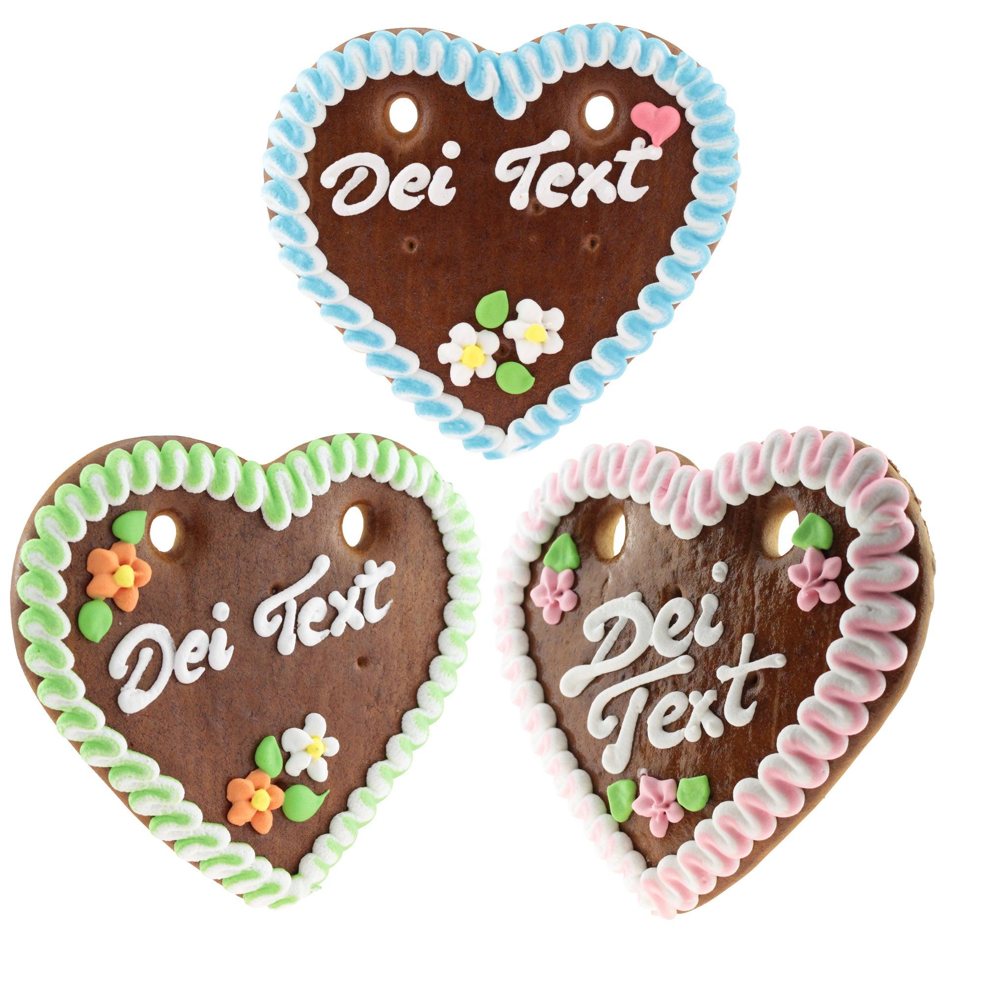 Braunes, herzförmiges Lebkuchenherz mit weiß-blauer Zuckerverzierung und personalisierbarem Schriftzug in Weiß; ca. 14 x 17 cm, 100 g.