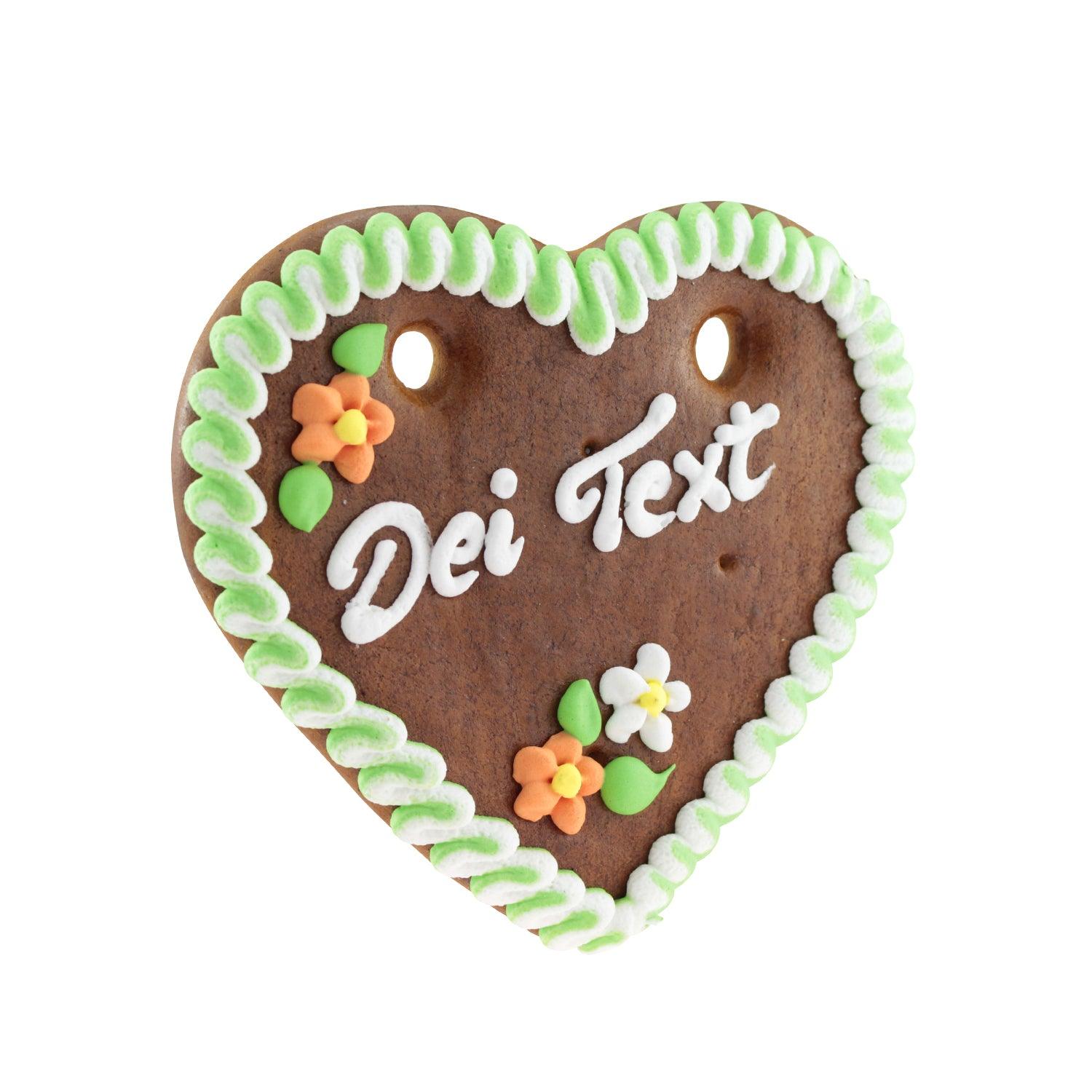 Herzförmiges Lebkuchenherz mit rot-weißem Rand, weißer Zuckerschrift und blauem Edelweiß-Dekor, personalisierbar.