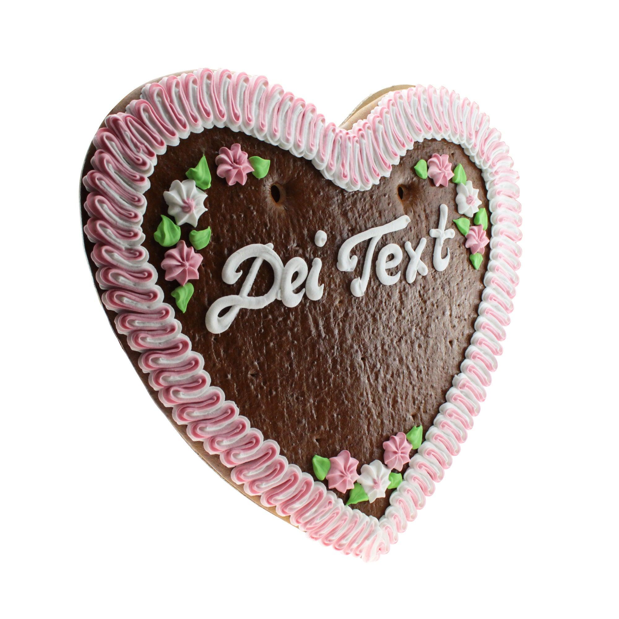 Großes herzförmiger Lebkuchen in Braun mit weißer Zuckerschrift, bunten Zuckerdekoren und Wunschtext, ca. 48×50 cm.