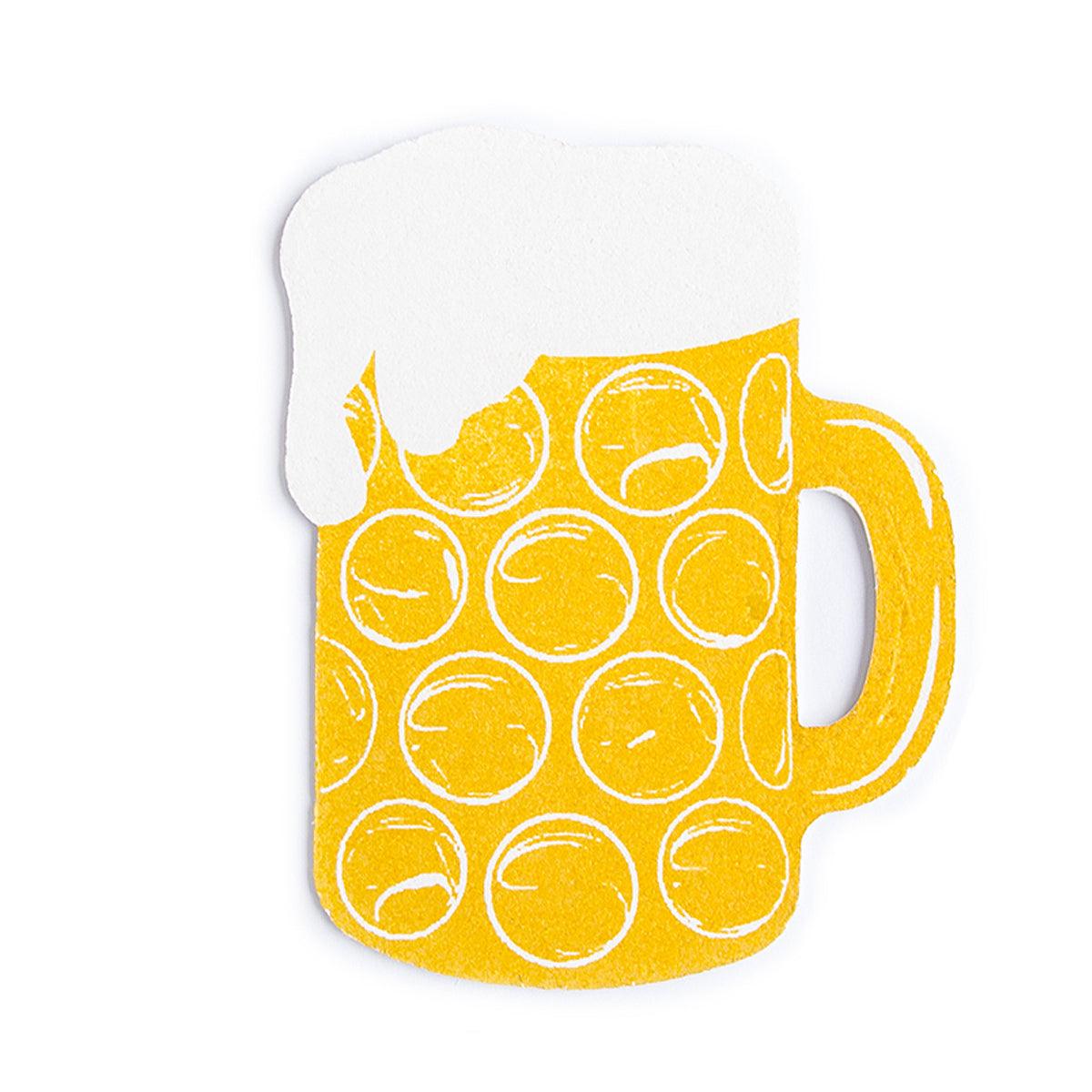 Beiger Schwamm in Form eines bayerischen Maßkrugs mit blauem Rautenmuster und aufgedrucktem Schriftzug, aus Zellulose, 11 × 8,7 cm.