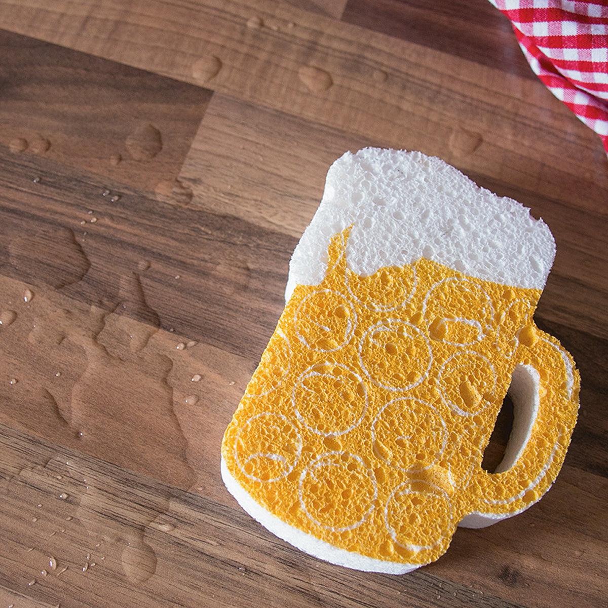 Maßkrugförmiger Schwamm aus gelber Zellulose mit blauem bayerischem Rautenmuster und Henkel; ca. 11 x 8,7 cm.