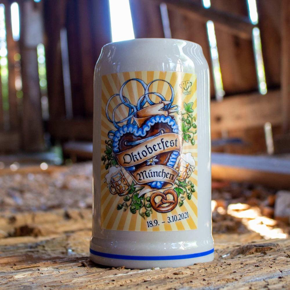 Oktoberfestkrug aus grauem Steingut mit Henkel, farbigem Plakatmotiv 2021 und blauem Schriftzug, 1 Liter.