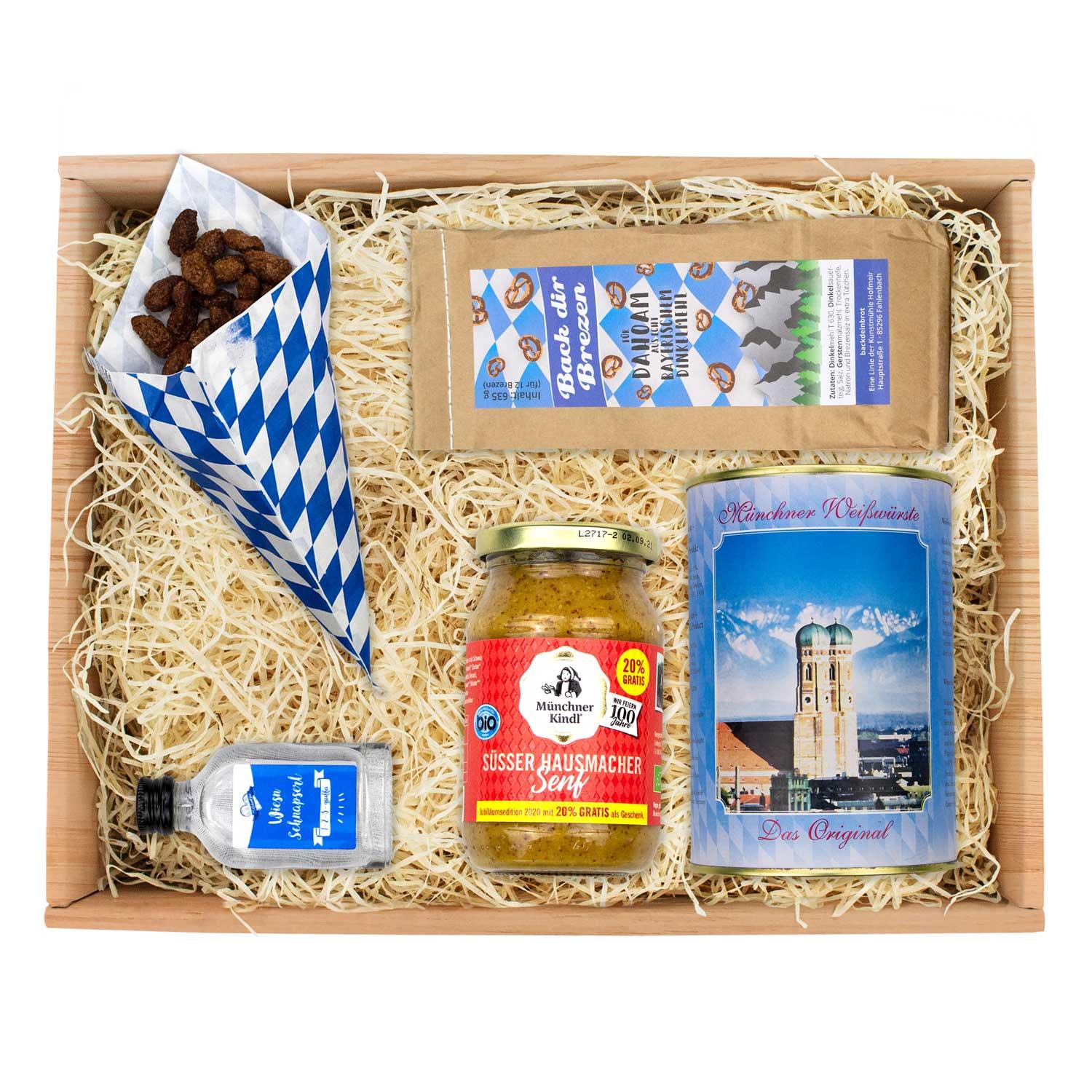 Oktoberfest-Box mit Weißwürsten in Glas, süßem Senf, Brezn-Backmischung und blau-weiß kariertem Serviettenmuster.