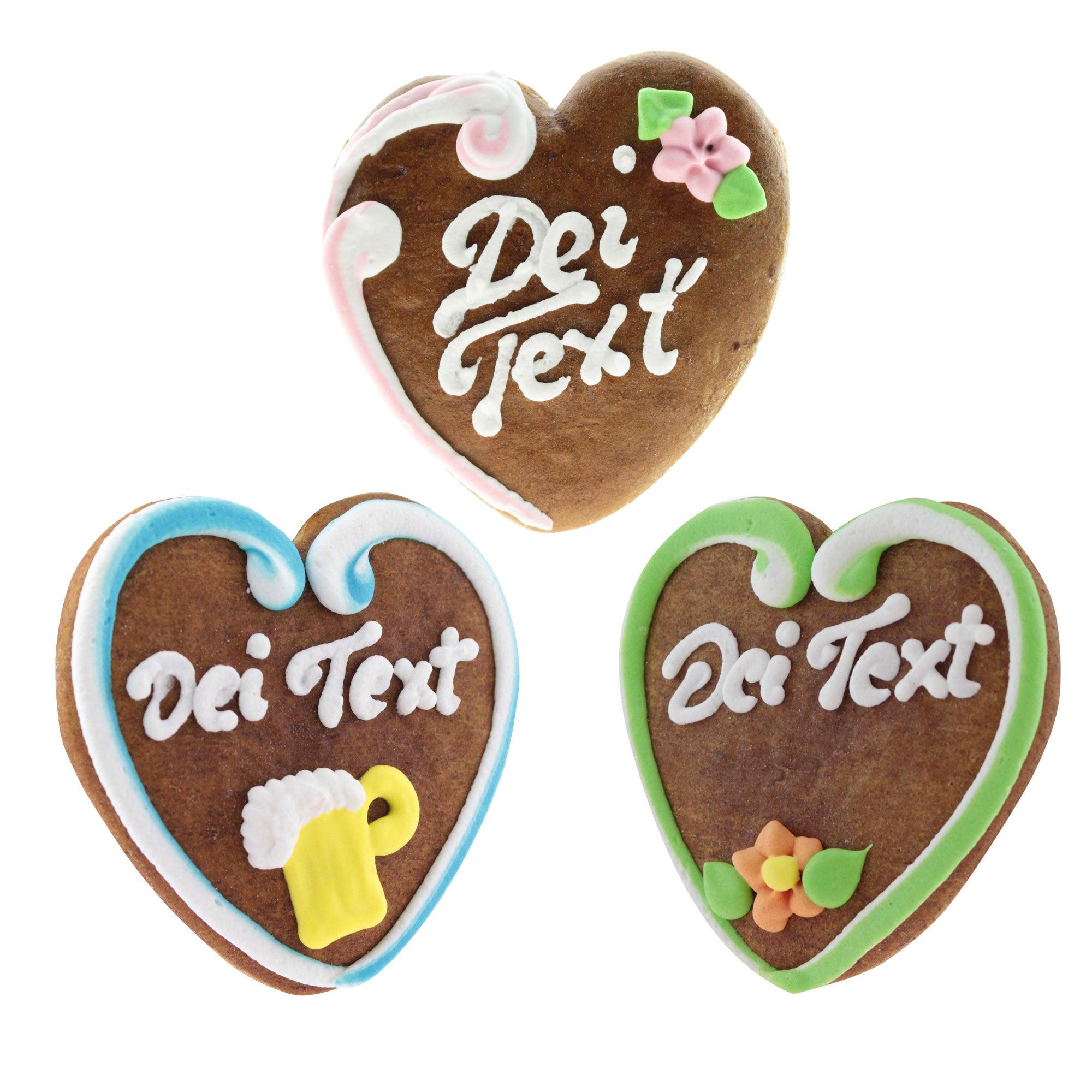 Braunes Lebkuchenherz mit weißer und rosafarbener Zuckerdekoration, pinkem Rand und individuellem Schriftzug, ca. 10 × 10 cm.