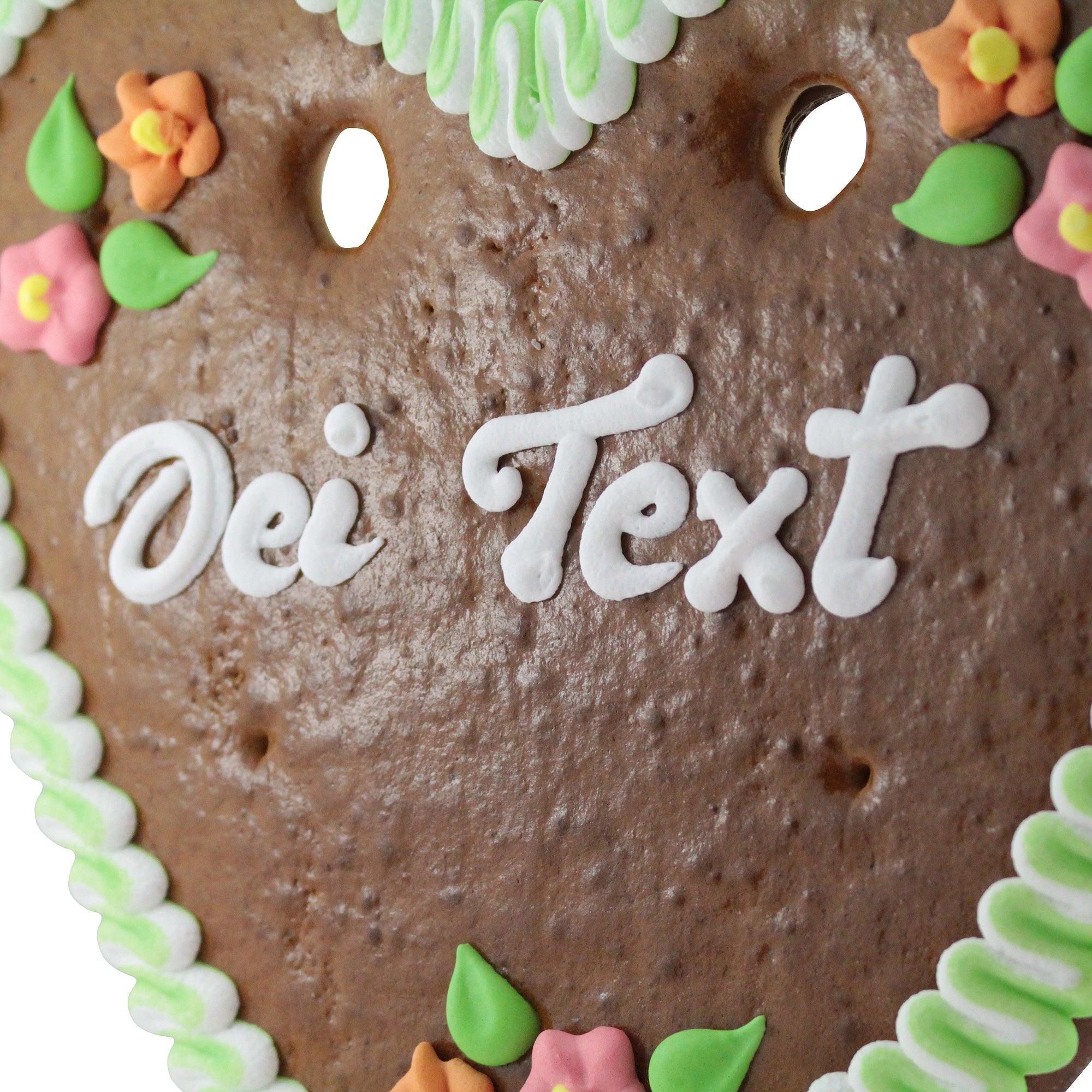 Herzförmiges Lebkuchenherz mit weiß-blauer Zuckerschrift und Rosenverzierung, individuell personalisierbar, ca. 32 × 28 cm.