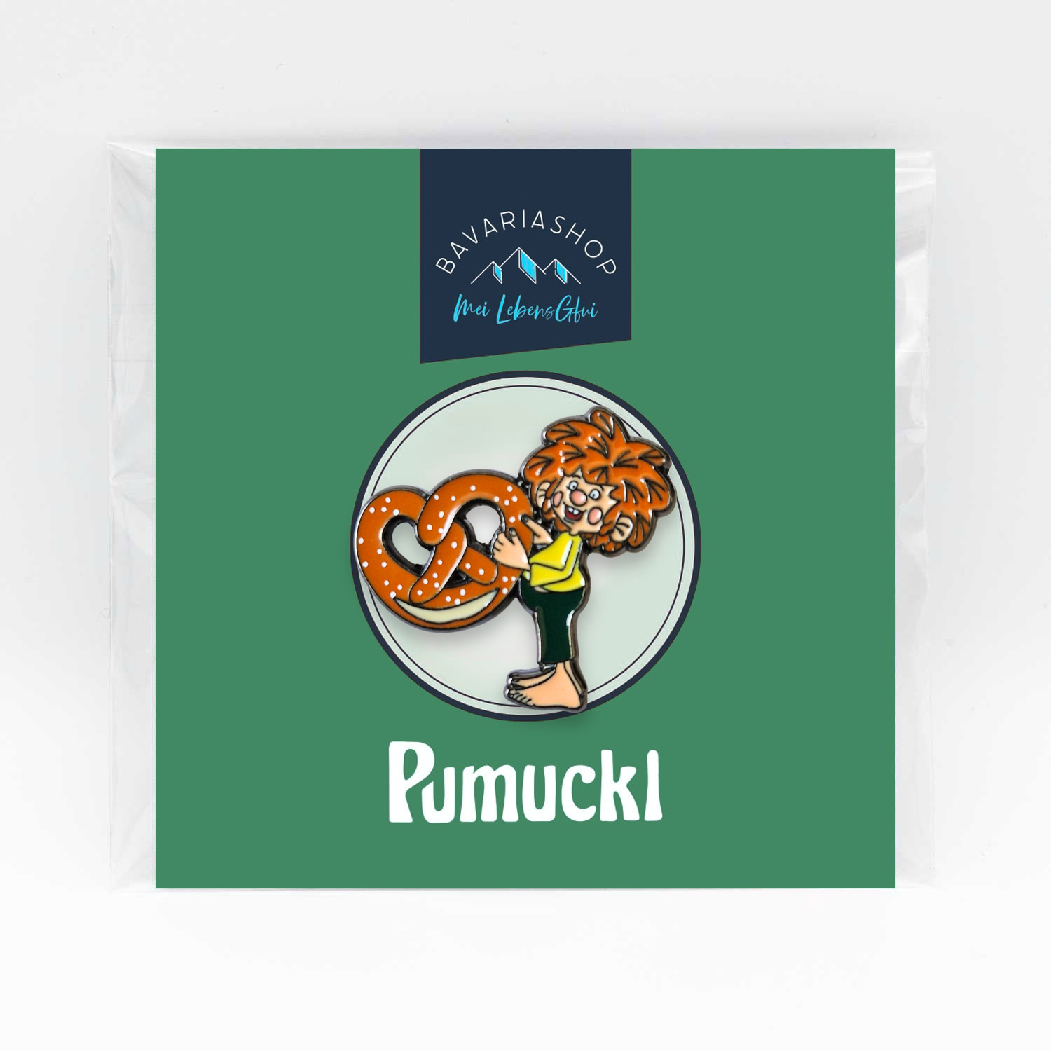 Pumuckl Motiv Pin mit rotem Haar, der eine goldbraune Brezel mit Salzkörnern hält, in Klarsichtfolie verpackt.