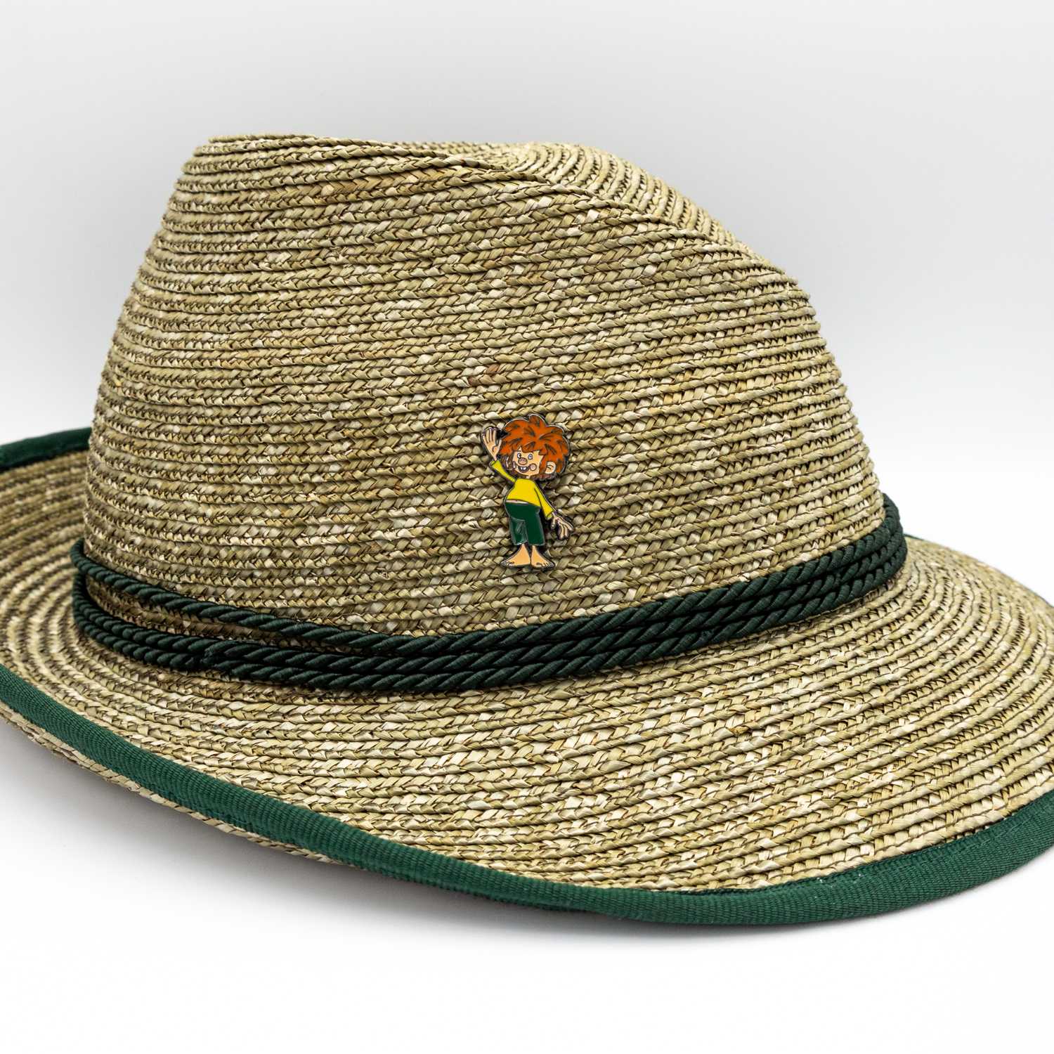 Eng limitierter Pumuckl Servus Pin mit dem Kobold beim Winken auf einem beigefarbenen Strohhut.