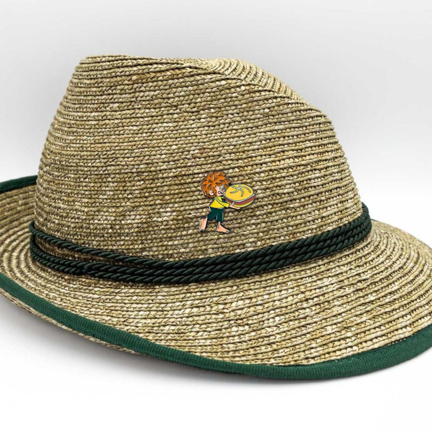 Pumuckl Pin mit Leberkassemmel Motiv auf einem traditionellen Strohhut mit grünem Band.