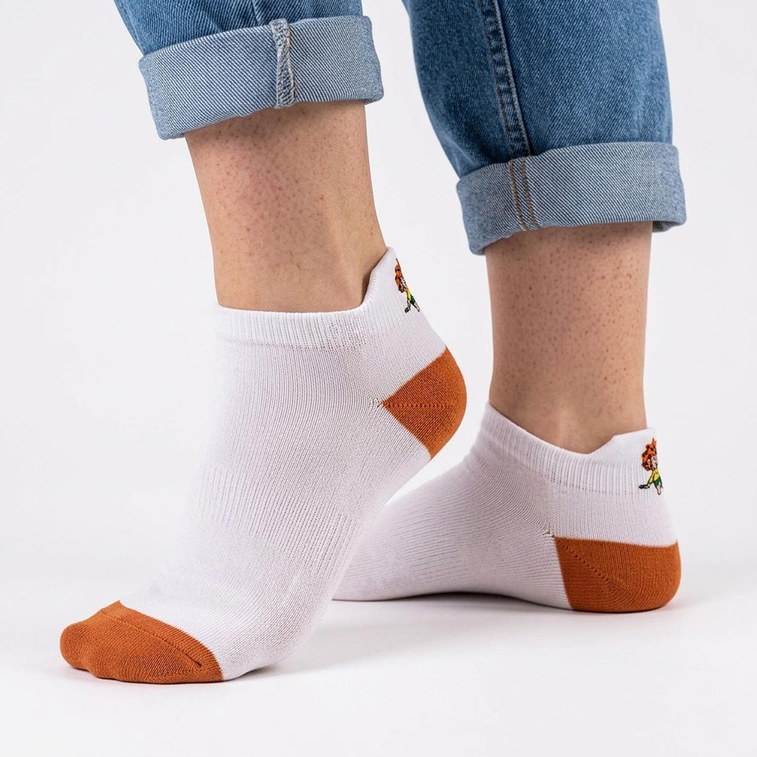 Weiß-braune Pumuckl Sneaker Socken mit kleinem Pumuckl-Motiv an der Ferse, getragen zu Jeans.
