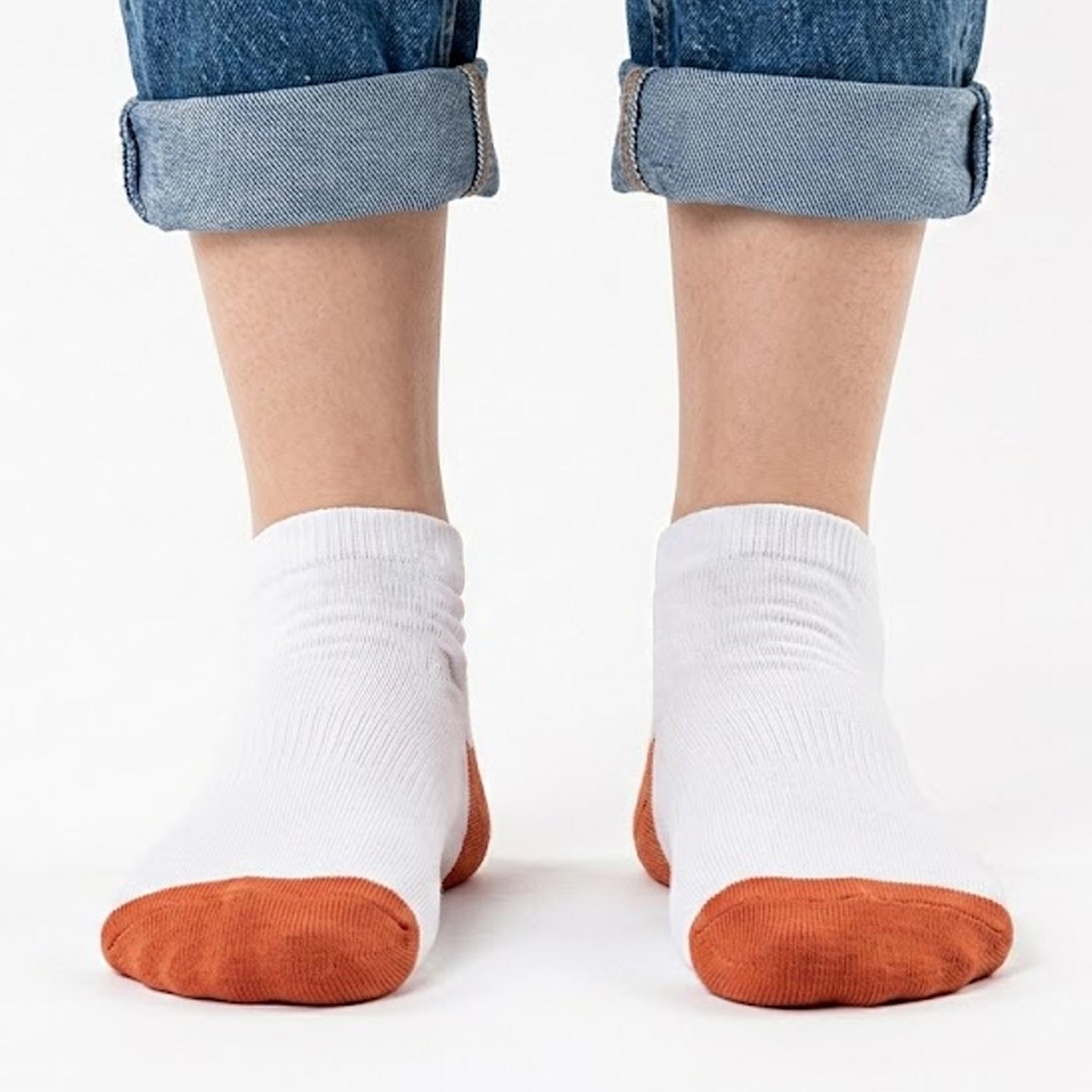 Weiße Pumuckl Sneaker Socken mit orangefarbener Spitze und Ferse, getragen mit hochgekrempelter Jeans