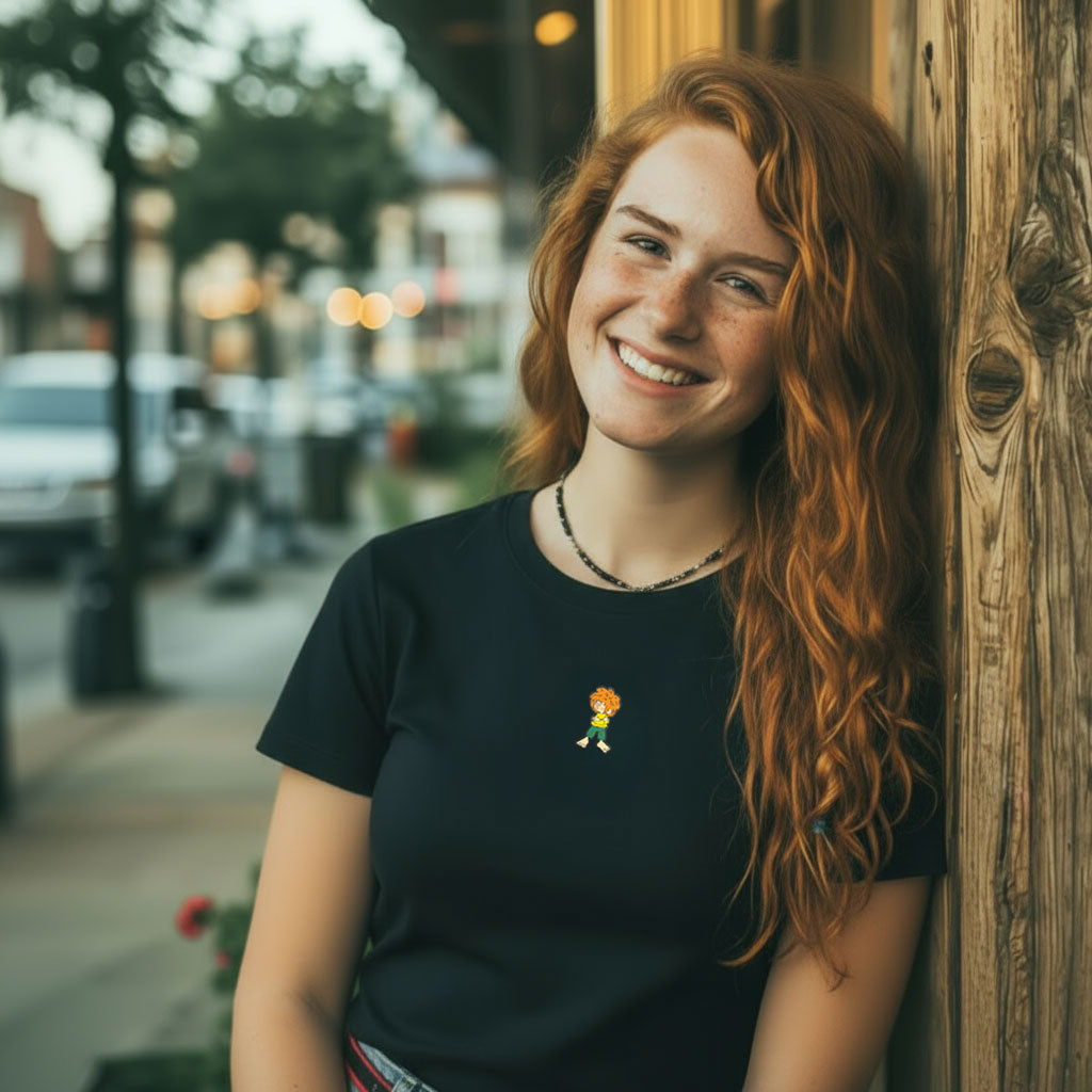 Lachende Frau mit rotem Haar trägt schwarzes ®Pumuckl Damen T-Shirt Grantla mit kleinem Pumuckl-Motiv.