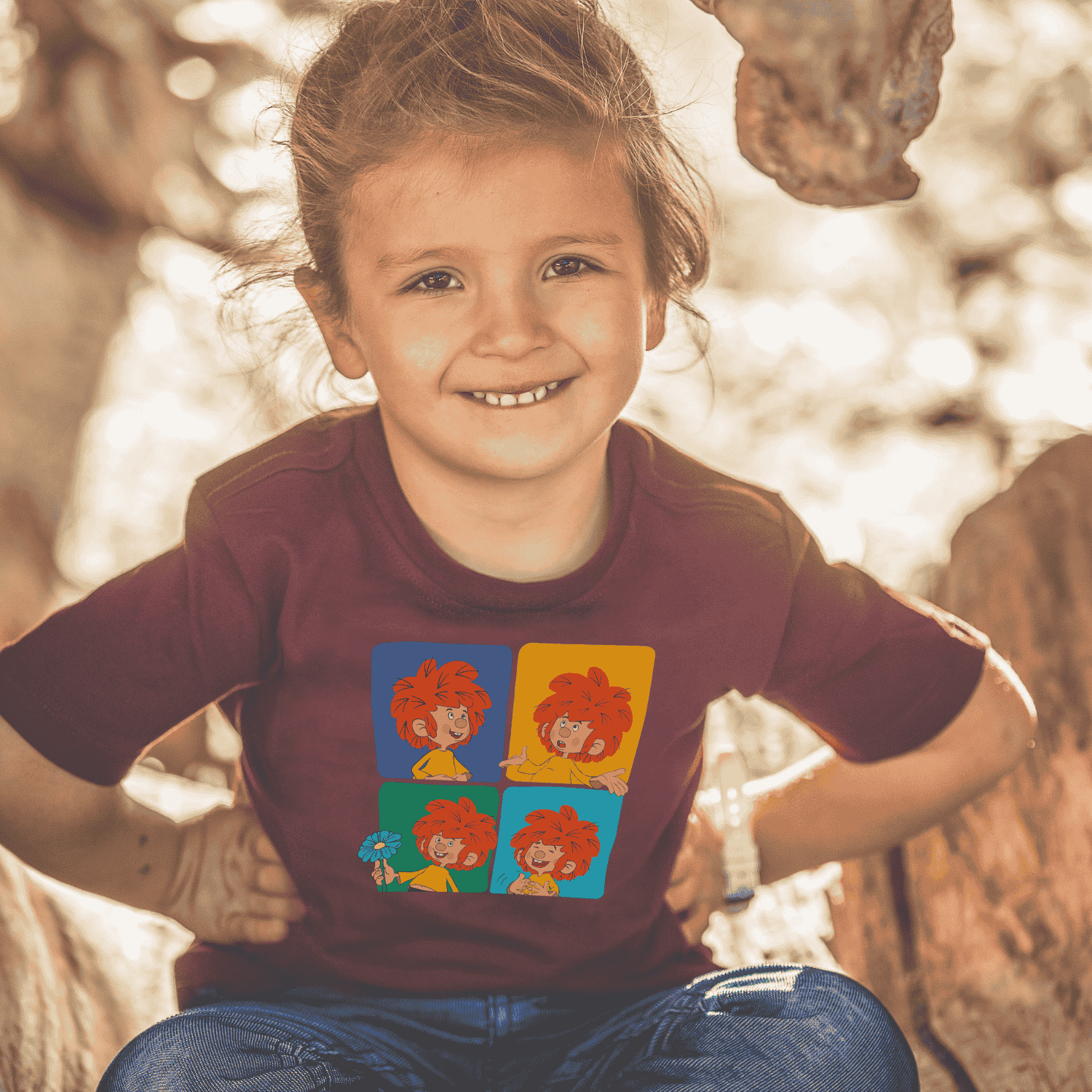 Lachendes Kind in einem burgunderroten Pumuckl Kinder T-Shirt Meisterwerk mit bunten Pumuckl Köpfen.