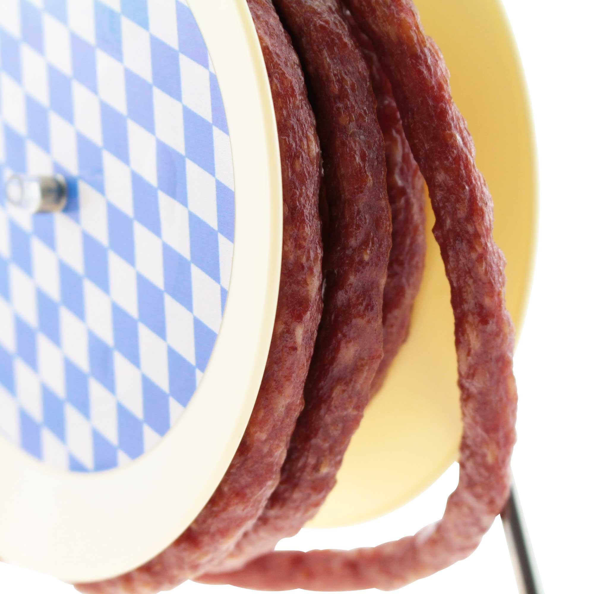 Lange Snackwurst auf rustikaler Kabeltrommel aufgerollt, rötlich-braune Farbe, ca. 3,5 m, 240 g.