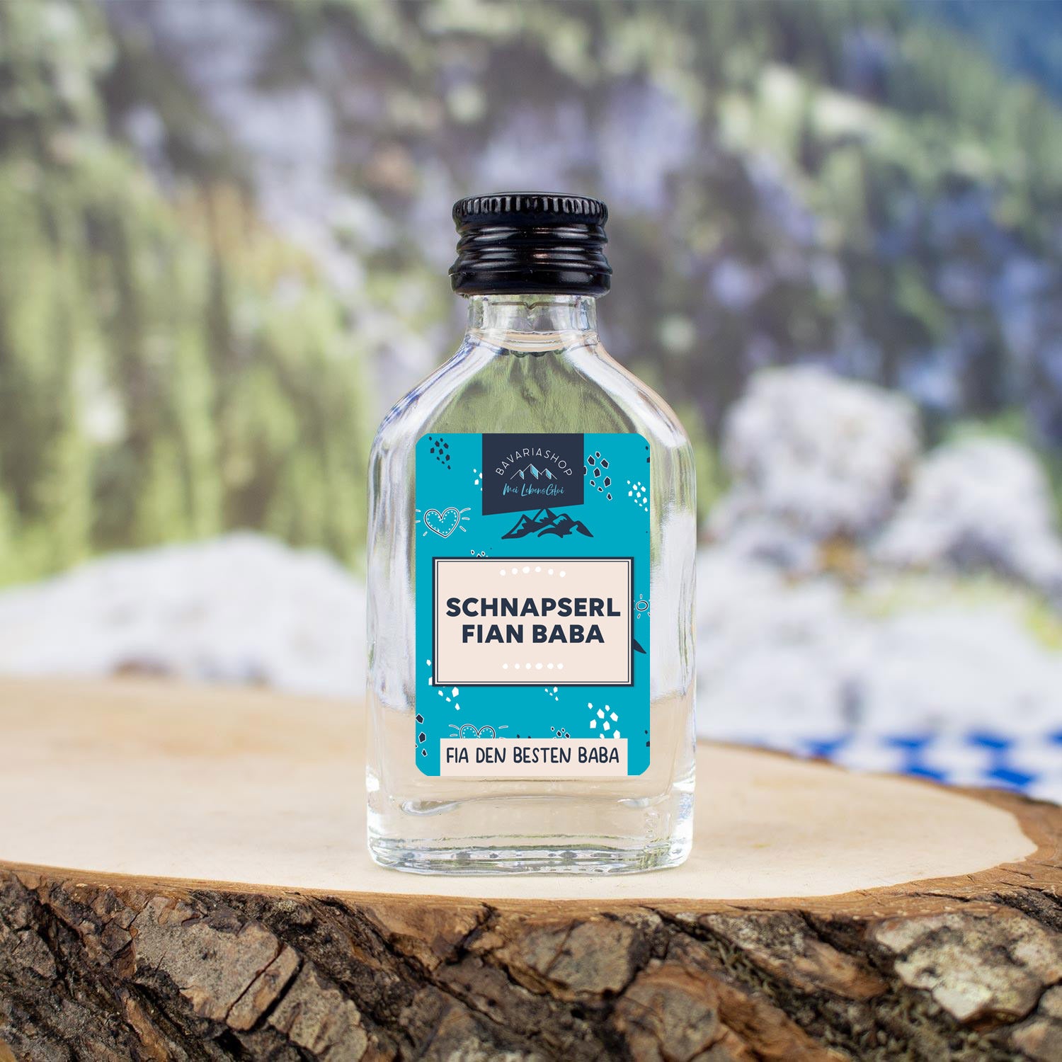 Kleine Schnapsflasche mit Aufdruck „fian Baba“, befüllt mit klarem Obstler, 38 % vol., 20 ml Inhalt.