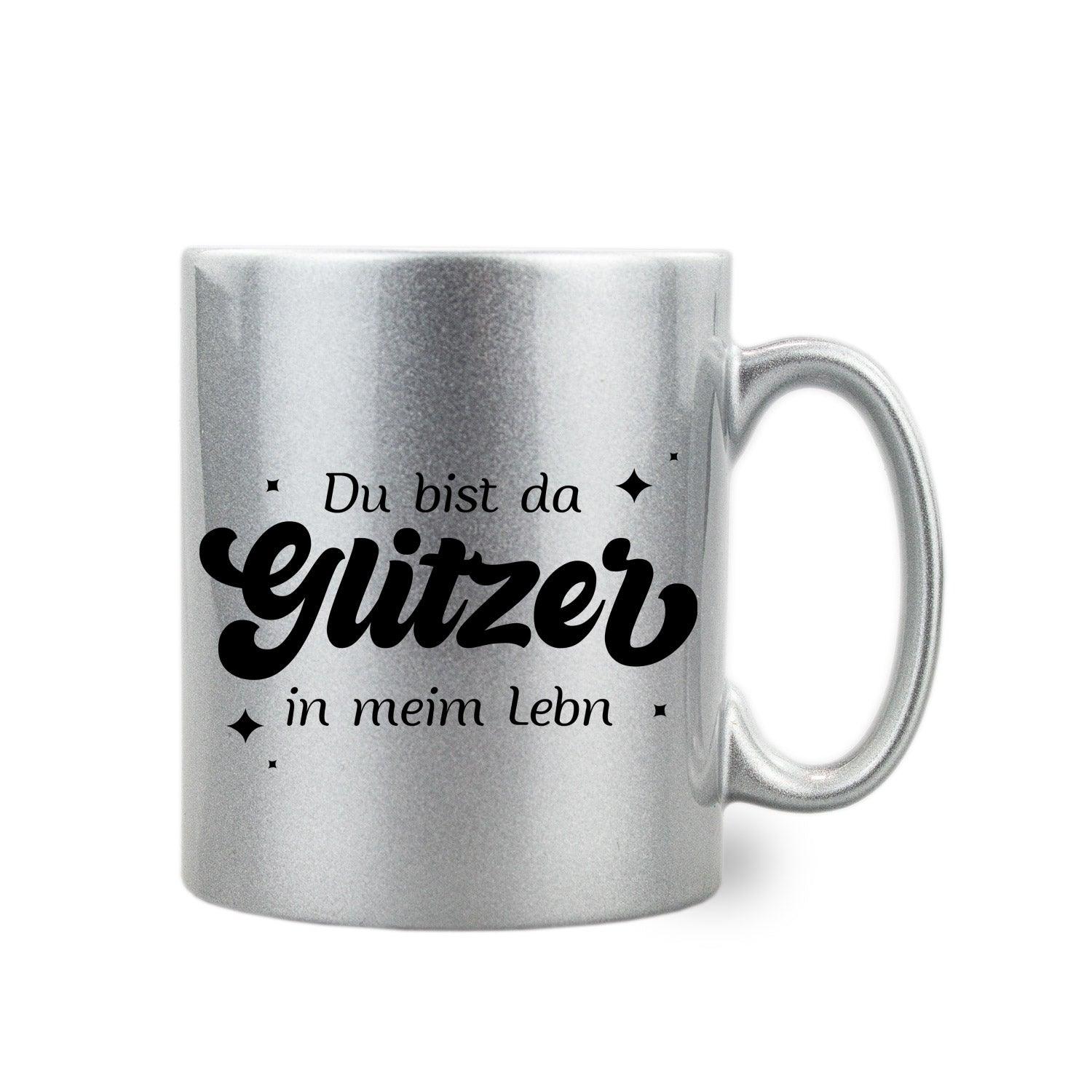 Silber-glitzernde Tasse mit geschwungenem Henkel und Aufdruck „Du bist da Glitzer in meim Lebn“, 300 ml, Thermotransferdruck.