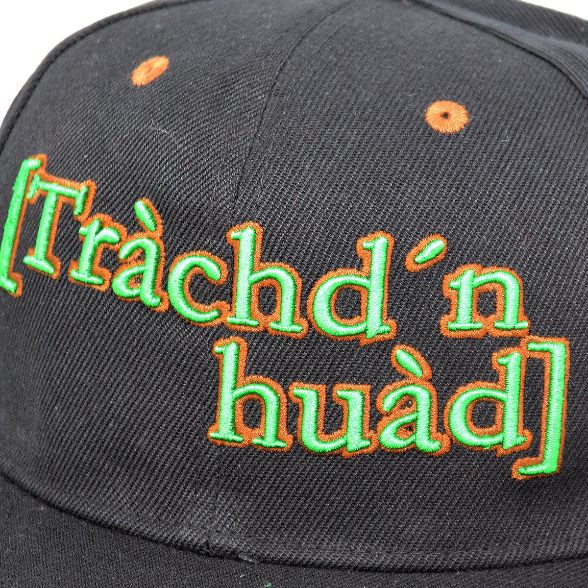 Schwarze Cap mit neongrüner und oranger Stickerei "Trachd'n huad", einem bayerischen Dialektwort, auf der Vorderseite.
