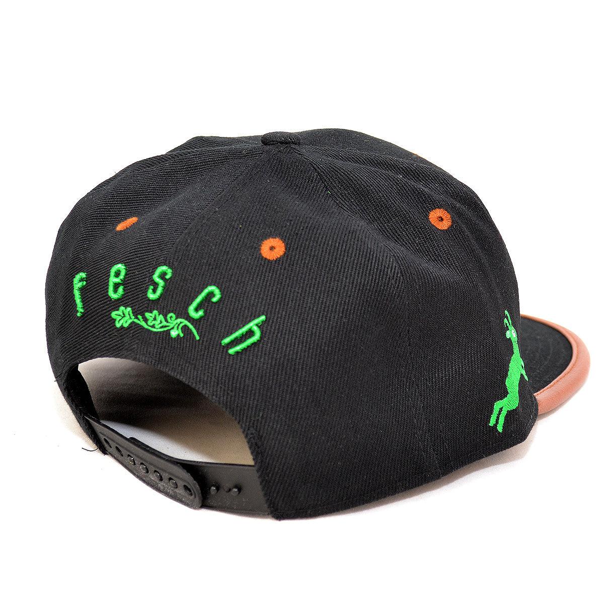 Schwarze Snapback Cap mit grüner fesch Stickerei, bayerischem Wappen und braunem Schirm Detail.