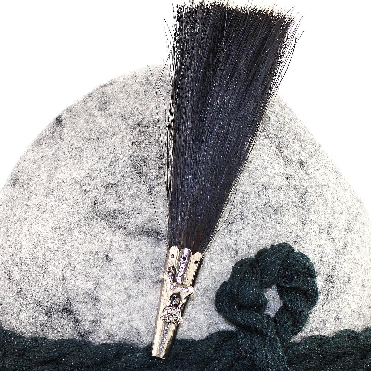 Traditioneller Gamsbart mit dicht gebundenen dunkelbraunen Haaren und verzierter Metallhülse mit Motiv, ca. 13 cm.