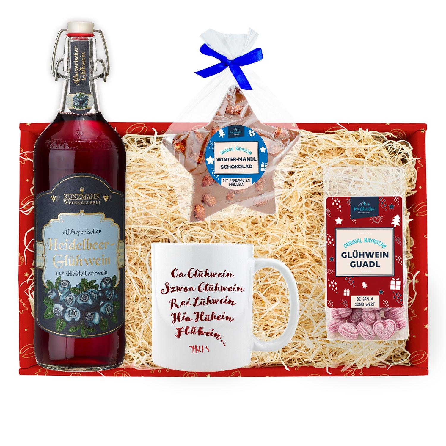 Weihnachtsbox mit Heidelbeer-Glühweinflasche, Glastasse mit „Glühwein“-Schriftzug und Beutel Glühweinbonbons.