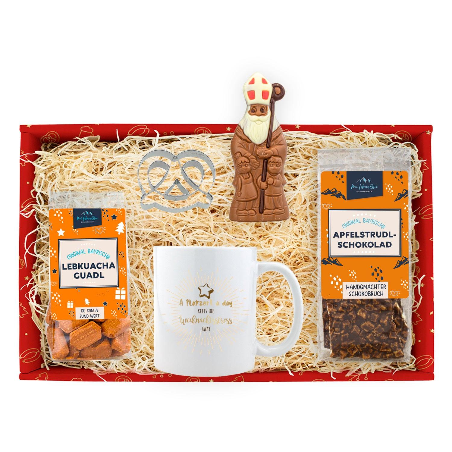 Weihnachtstasse mit rotem Rand und „Platzerl“-Schriftzug, Brezn-Ausstechform und Lebkuchenplätzchen.