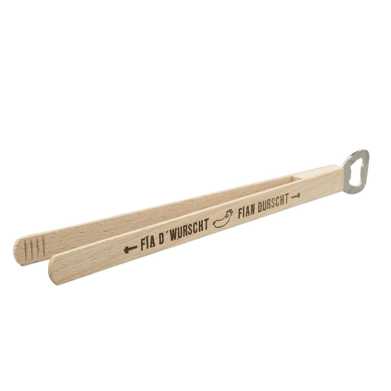 Lange Edelstahlzange mit Holzgriff, eingebautem Flaschenöffner und graviertem Schriftzug „Fia d’Wurscht – fian Durscht“.