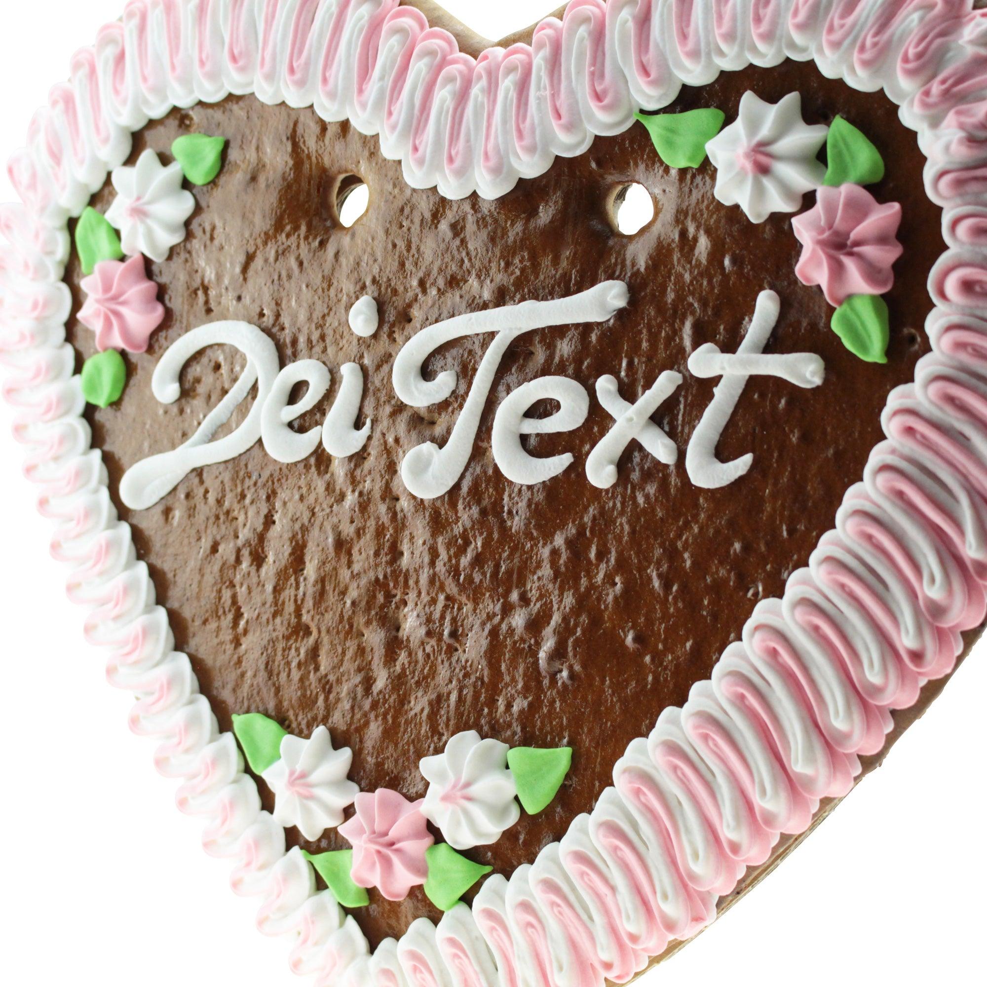 Herzförmiger Lebkuchen mit Zuckergussrand, rosa Rosenverzierung und weißem Schriftzug auf braunem Teig, ca. 36 × 34 cm.
