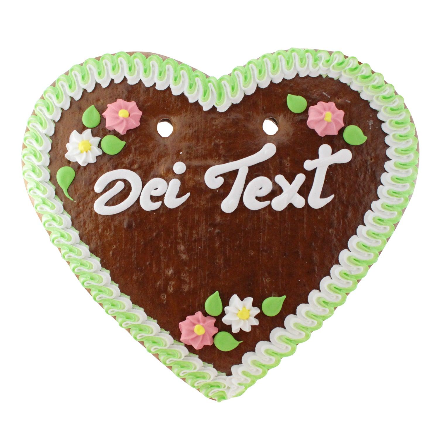 Herzförmiges Lebkuchenherz mit rot-weißem Zuckerrand, weiß-blauer Blumenverzierung und weißem Schriftzug, ca. 34 × 36 cm, 500 g.