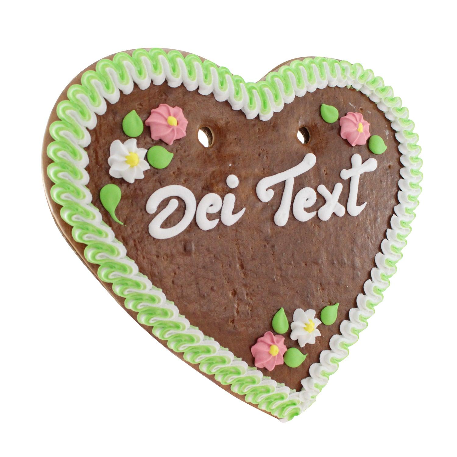 Herzförmiges Lebkuchenherz aus braunem Teig mit rosa Rand, bunter Blumendeko und weißem Zuckerschriftzug; ca. 36 × 34 cm, 500 g.