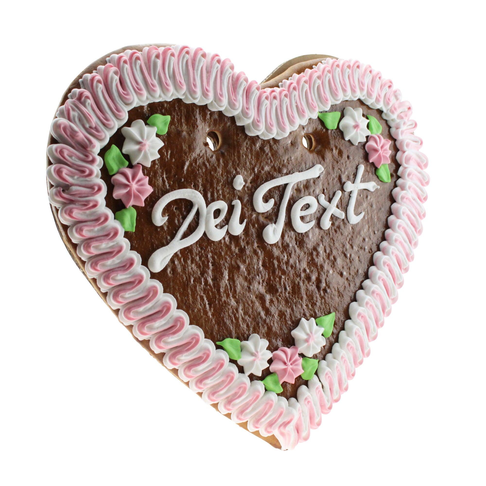 Herzförmiges Lebkuchen mit weißer Zuckerschrift und Verzierung aus Zuckerguss, detailreich verziert in Blau, Rosa und Weiß.