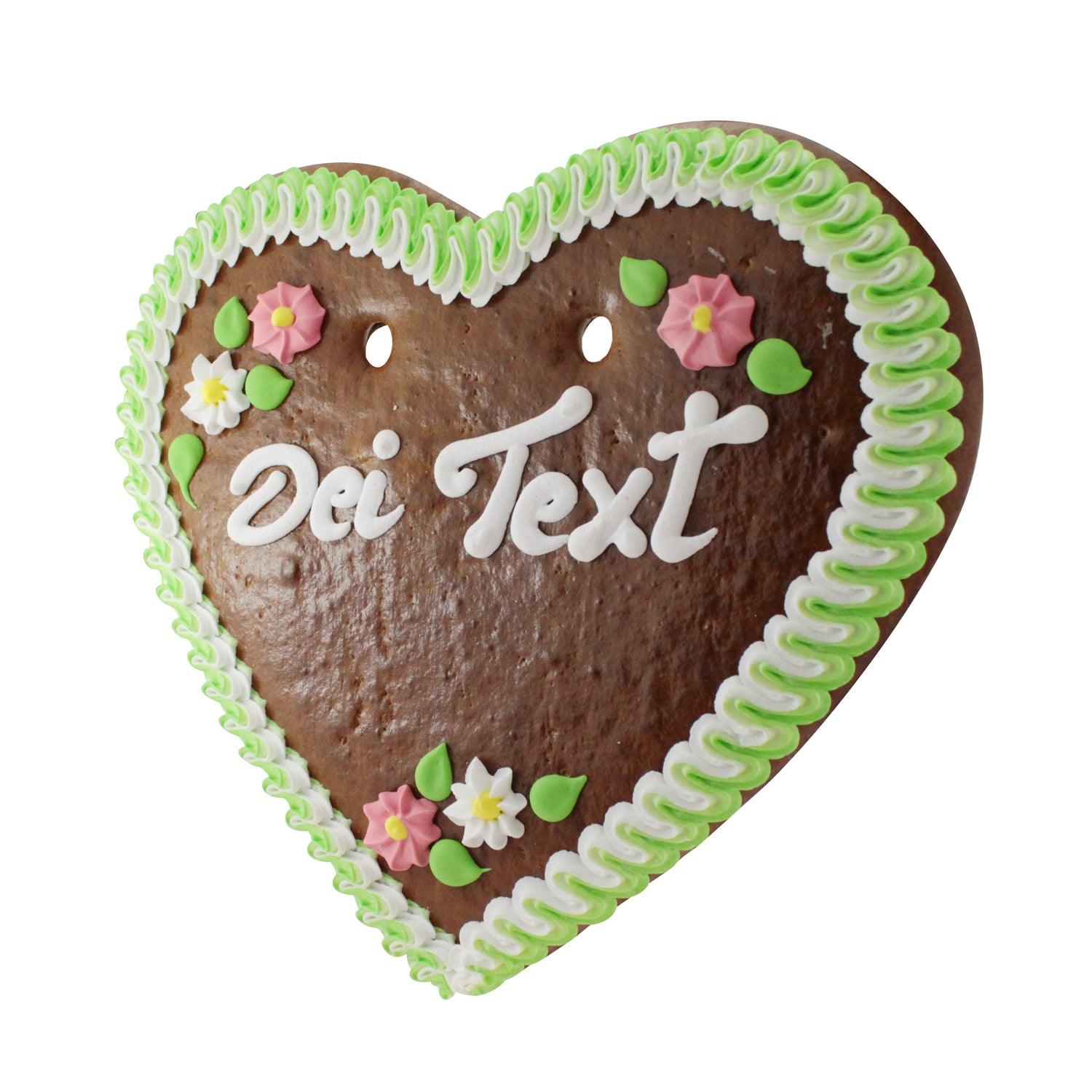 Herzförmiger Lebkuchen mit weißer und rosa Zuckerglasur, rosafarbenem Schriftzug und bunten Blumendekoren, ca. 36 × 34 cm.