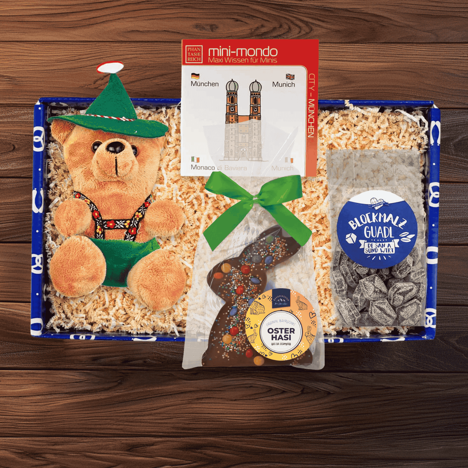 Plüschbär mit Lederhose, ovale Osterschokolade mit Hasenrelief, Blockmalzbonbons in Geschenkschachtel.