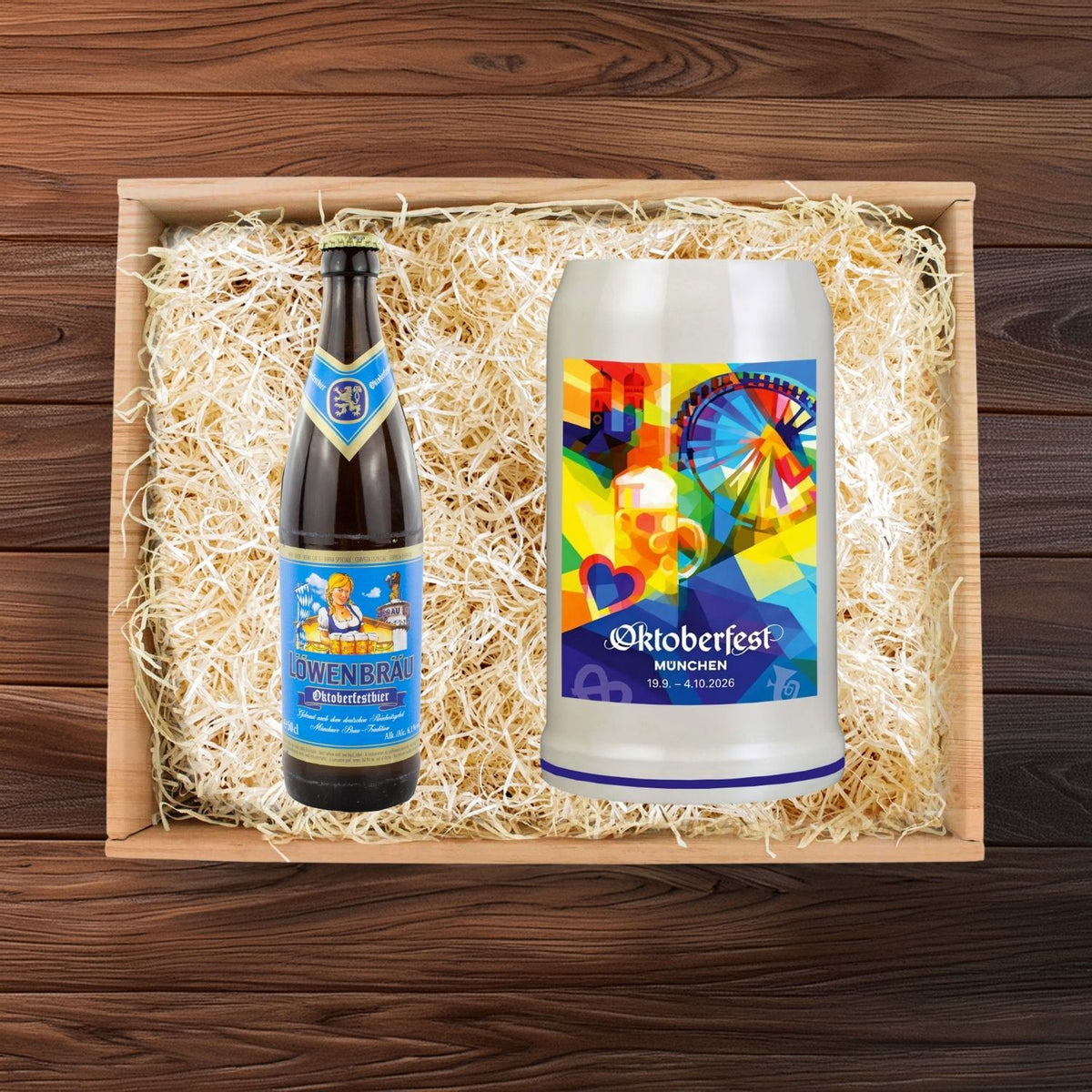 Oktoberfest Geschenkbox mit Löwenbräu Bierflasche und Wiesn-Maßkrug 2026 im bunten München-Design auf Holzwolle.