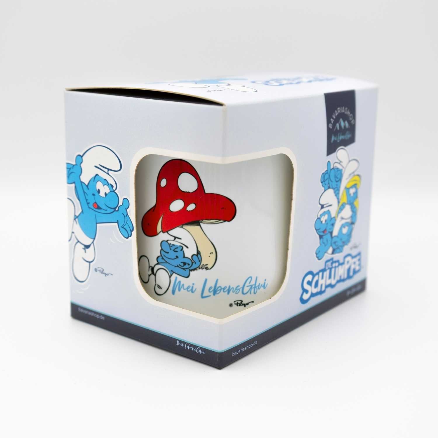 Weiße Emailletasse mit blauem Rand, Schlumpf-Motiv und bayerischem Schriftzug „Do legst di nieda“, ca. 330 ml.