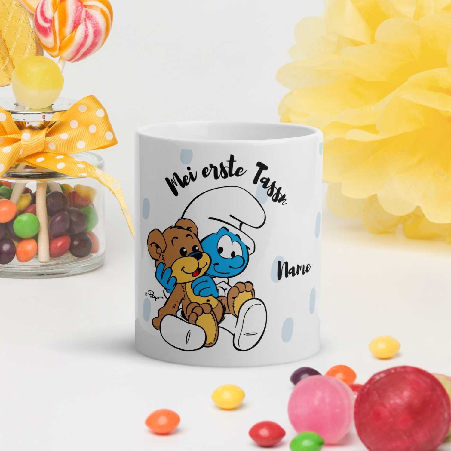 Weiße Porzellantasse mit farbigem Schlumpf-Motiv und bayerischem Schriftzug „Mei erste Tassn“, 330 ml Fassungsvermögen.