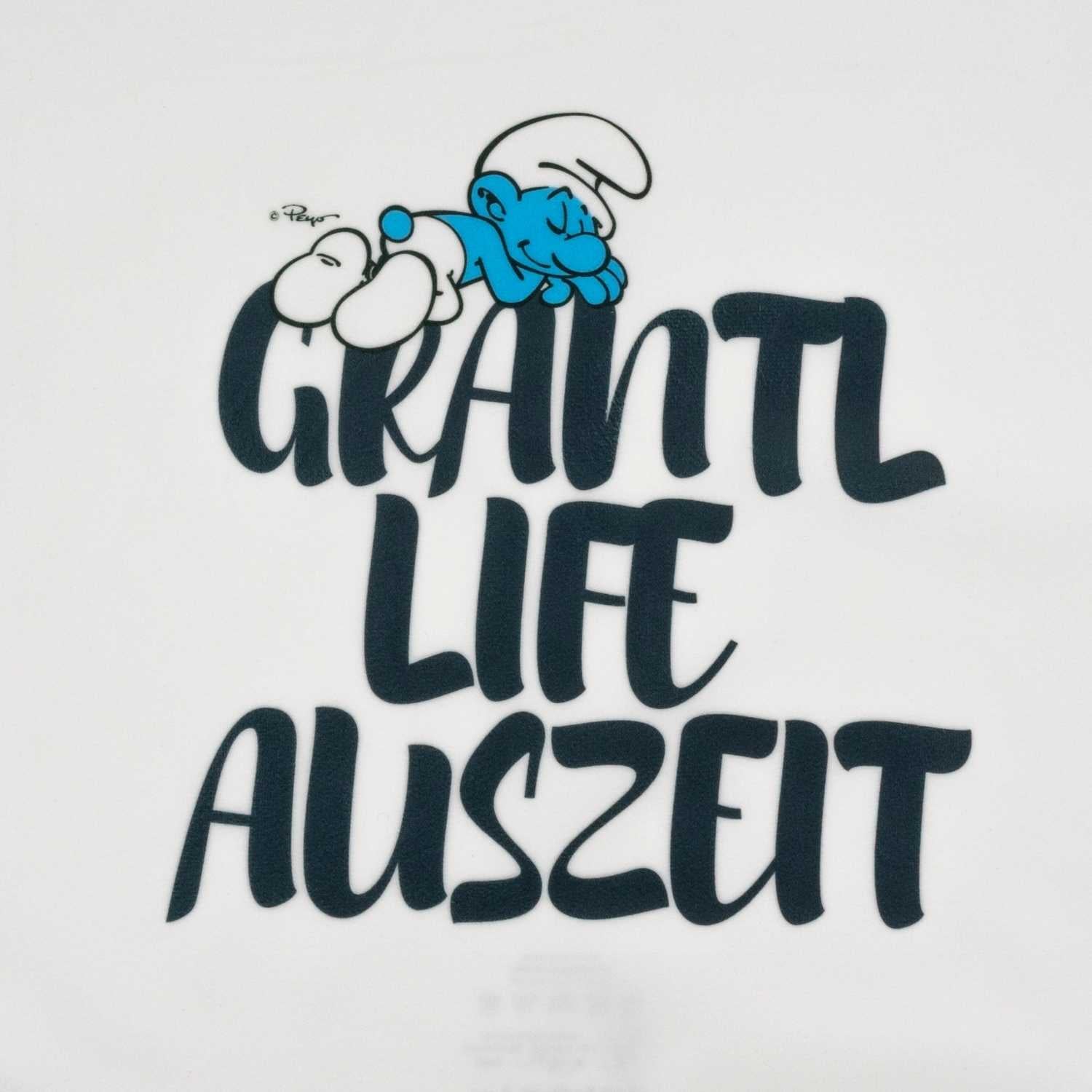 Quadratisches Dekokissen mit weicher Oberfläche, Schlumpf-Motiv und dem Schriftzug „Grantl Life Auszeit“.