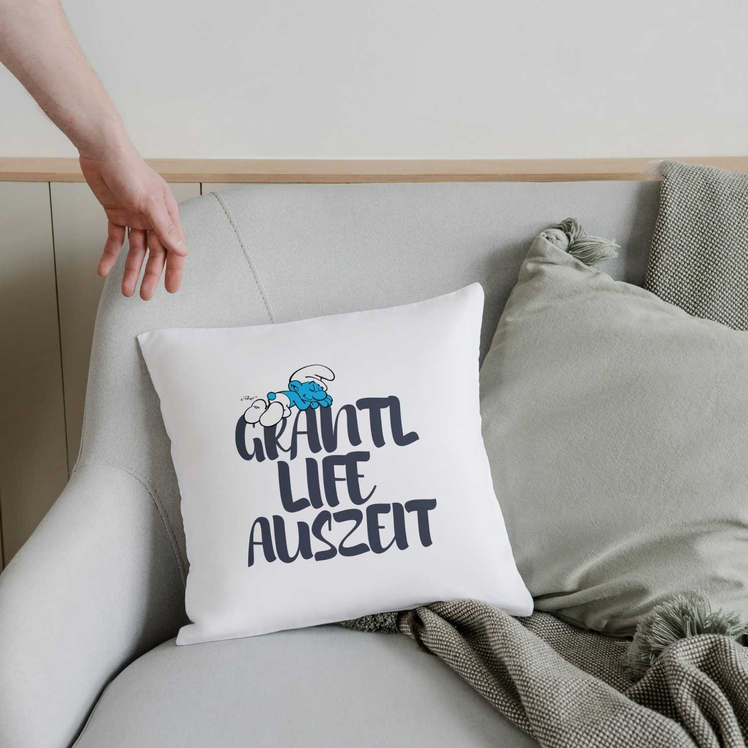 Quadratisches Kuschelkissen mit Schlumpf-Motiv und großem „Grantl Life Auszeit“-Schriftzug vorne.