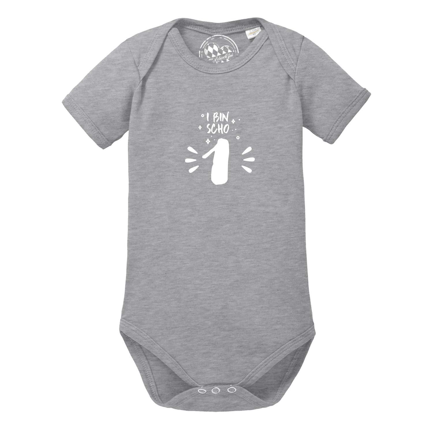 Grauer Baby Body "I bin scho 1!" mit weißem Aufdruck und kurzem Arm für den ersten Geburtstag.