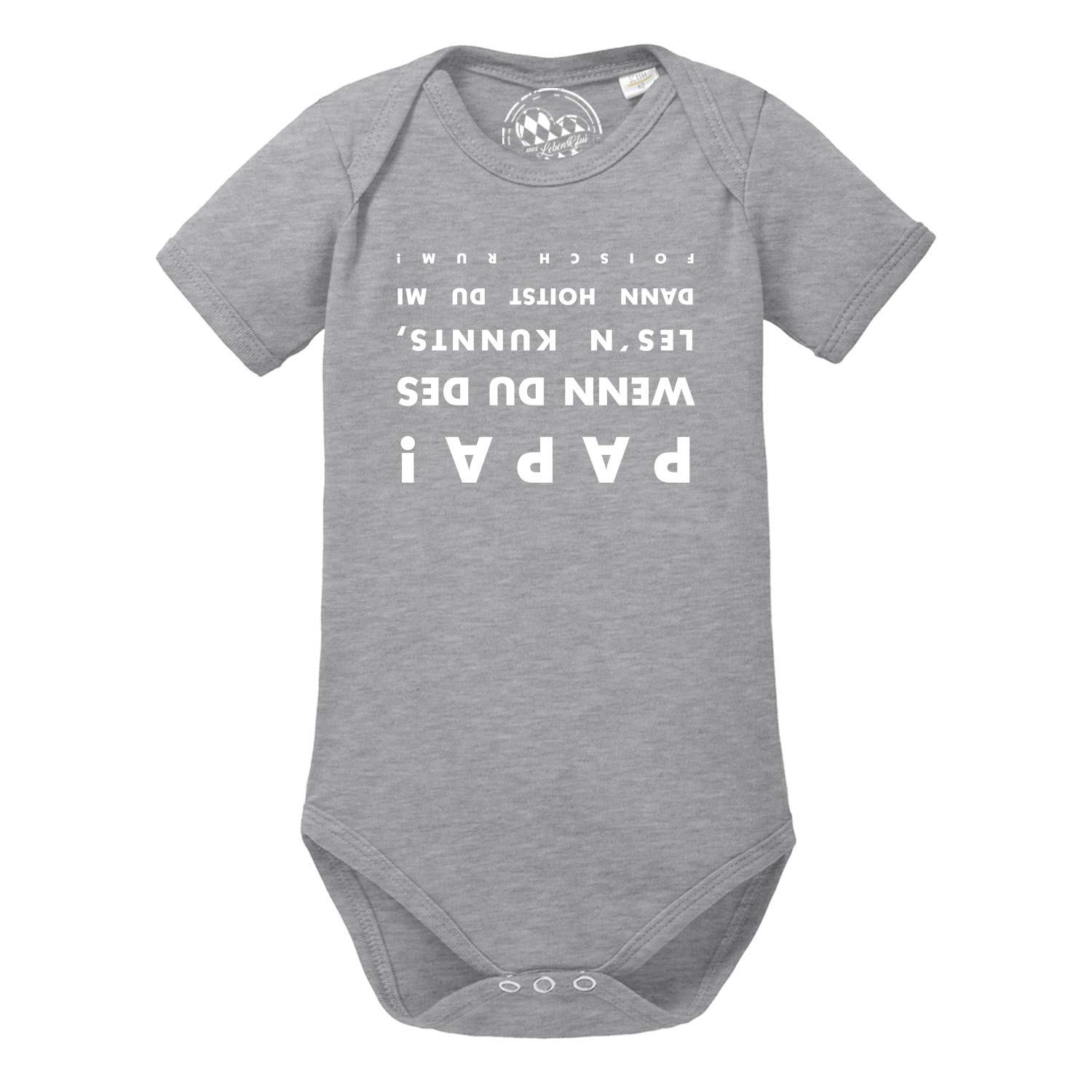 Weißer Babybody mit kurzem Arm, schwarzem Schriftzug „falsch rum“ vorn und kleinem Herzmotiv; aus Baumwolle.
