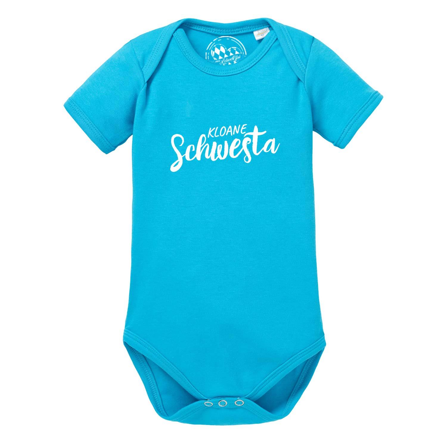 Weißer Babybody mit kurzen Ärmeln, rosa Schriftzug „Kloane Schwesta“ und bayerischem Herz-Motiv aus Baumwolle.