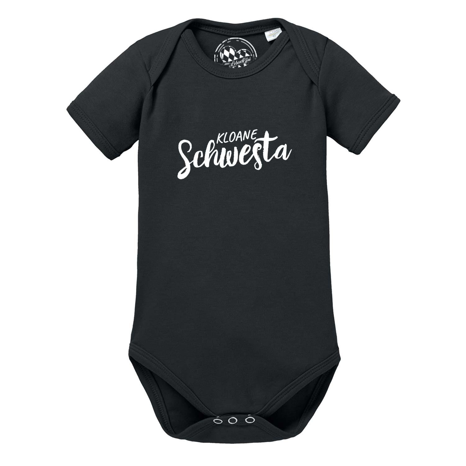 Weißer Babybody mit kurzen Ärmeln und rosa Aufdruck „Kloane Schwesta“ in geschwungener Schrift, reine Baumwolle.