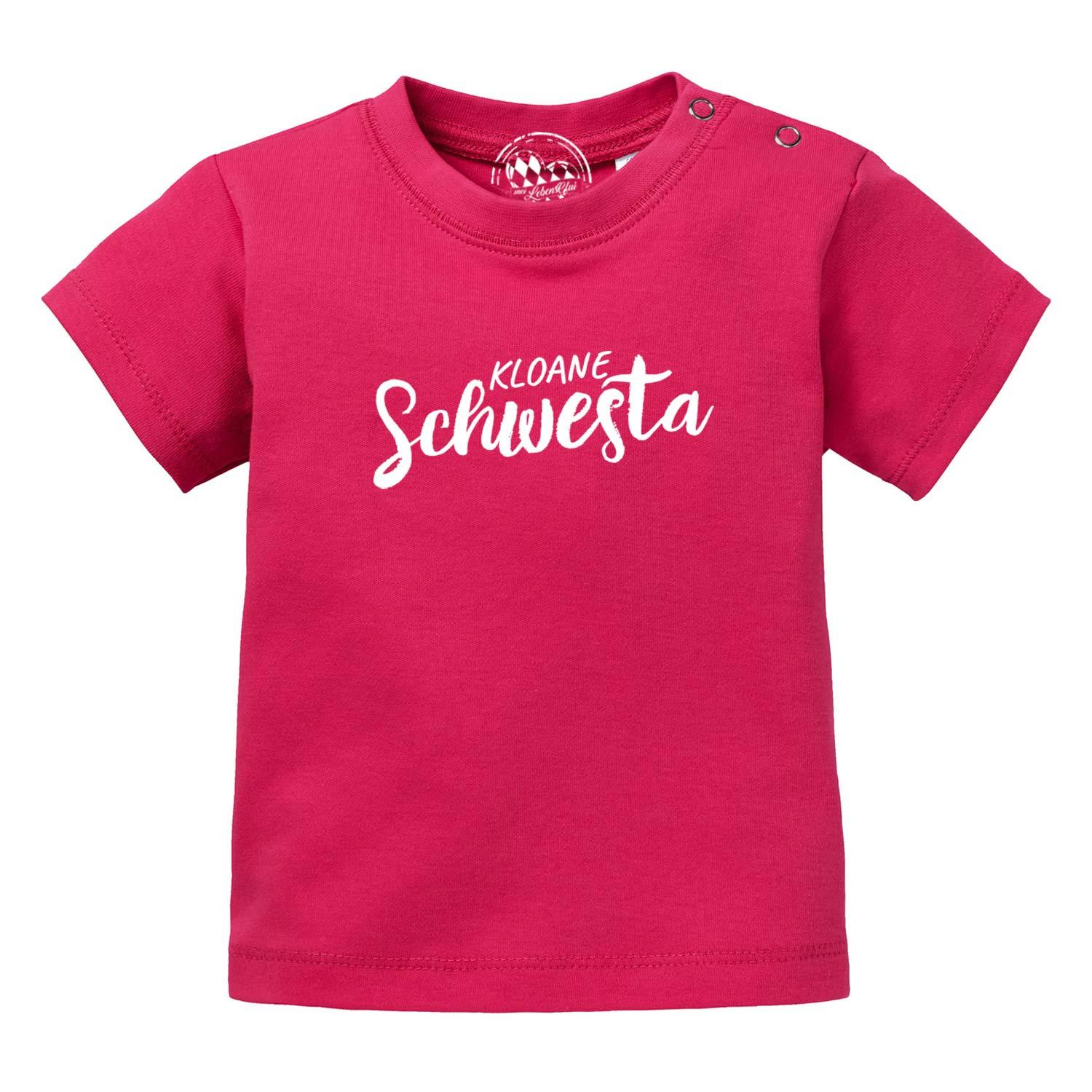 Hellrosa Baby-T-Shirt mit Aufdruck „Kloane Schwesta“ in Weiß, kurzer Ärmel, aus 100 % Bio-Baumwolle.