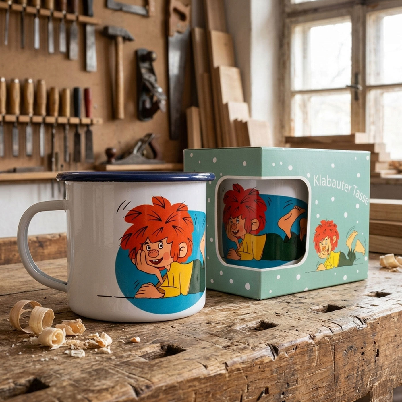 Pumuckl Emaille-Tasse Schaumamoi mit lustigem Elfenmotiv und Geschenkbox auf Werkbank.