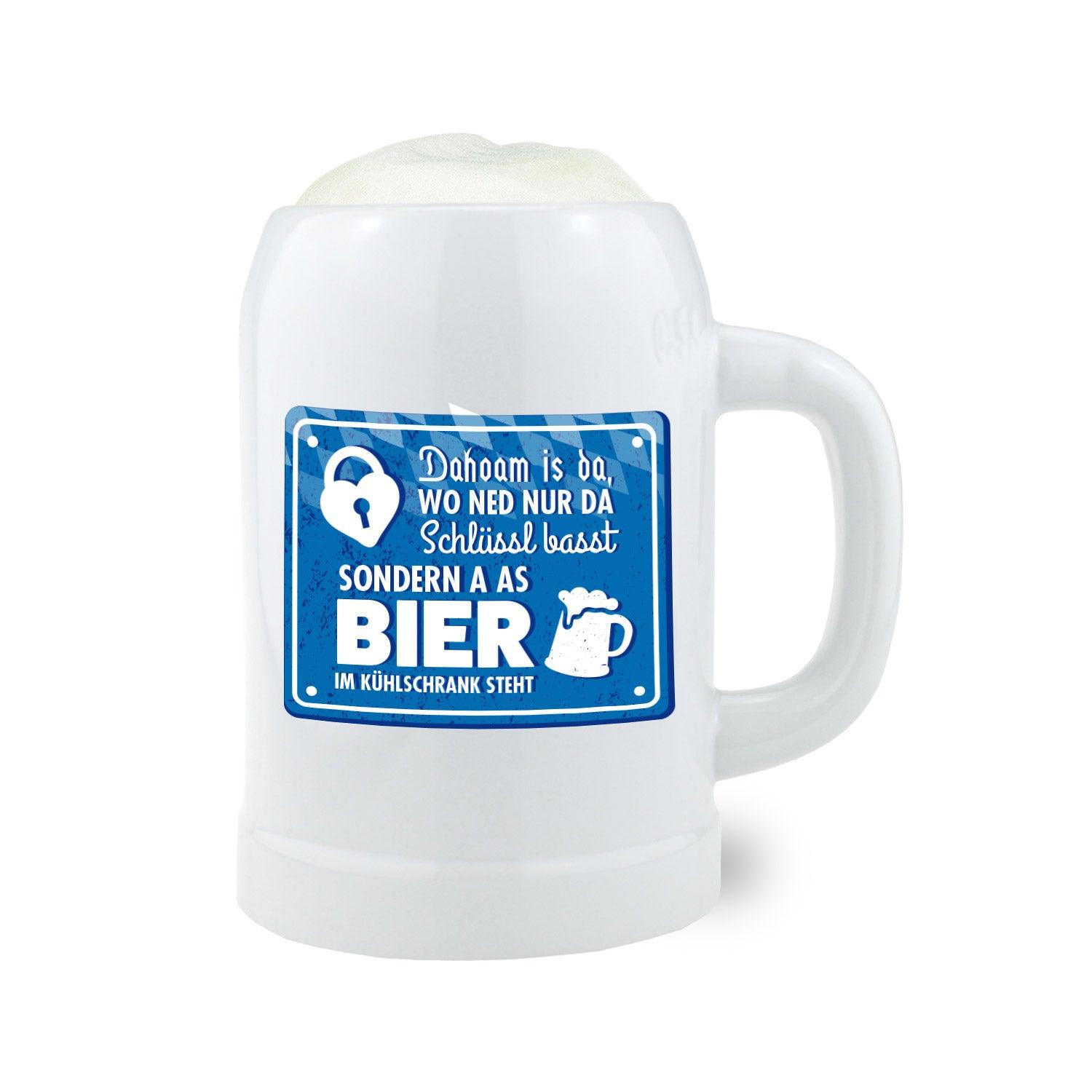 Keramik-Bierkrug mit weiß-glänzender Oberfläche, in klassischer Form, blauem „Dahoam“-Schriftzug und 0,5 l Füllvolumen.