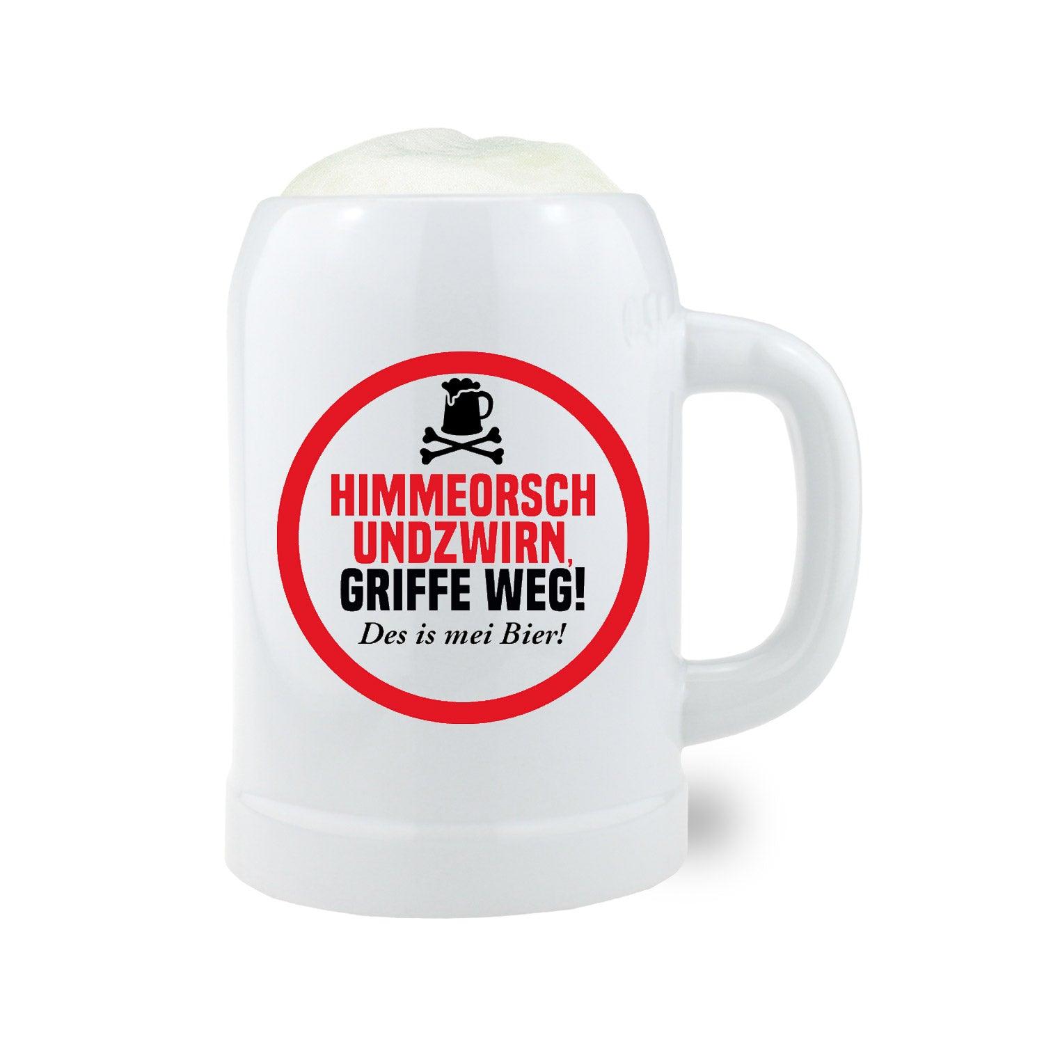Weißer Bierkrug Himmeorschundzwirn mit rotem Spruch "Himmeorsch undzwirn, Griffe weg! Des is mei Bier!" und Bierschaum.