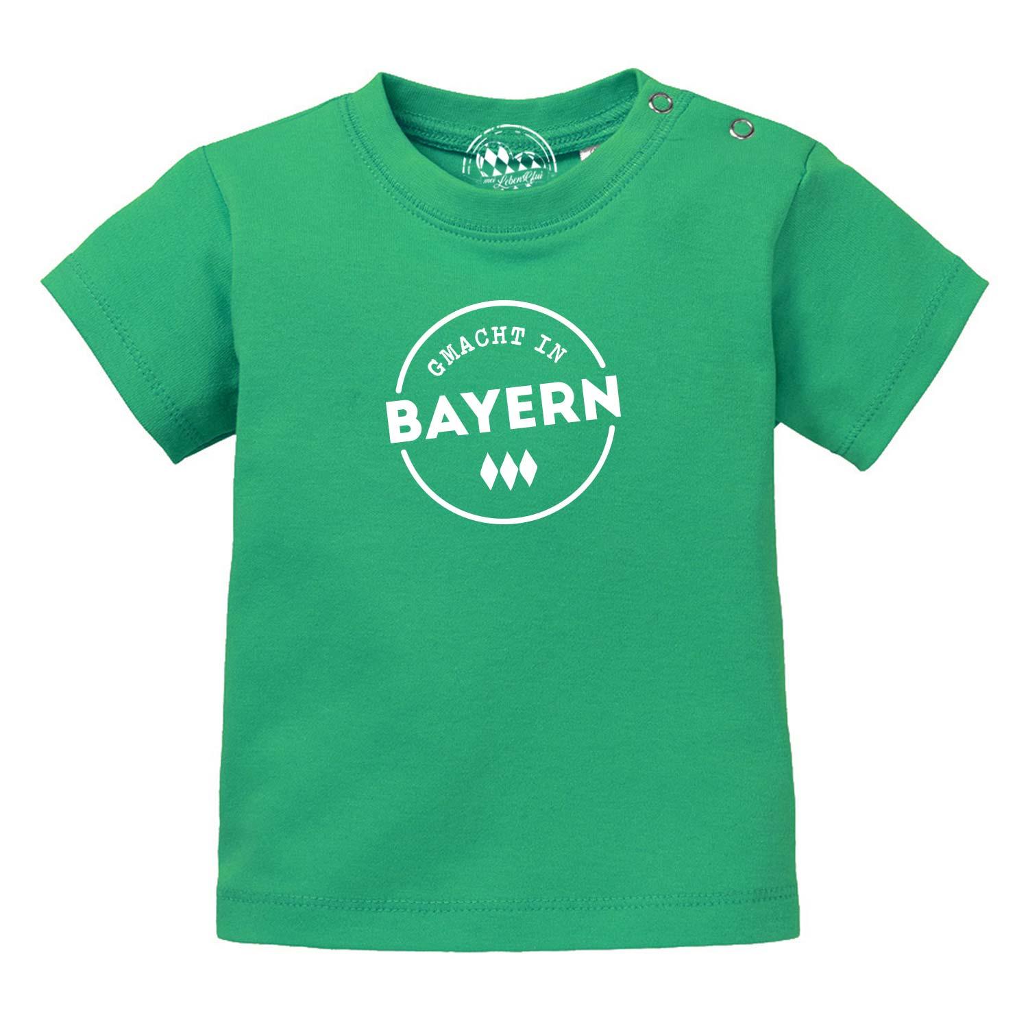 Grünes Baby T-Shirt Gmacht in Bayern mit weißem Schriftzug und Druckknöpfen an der Schulter.