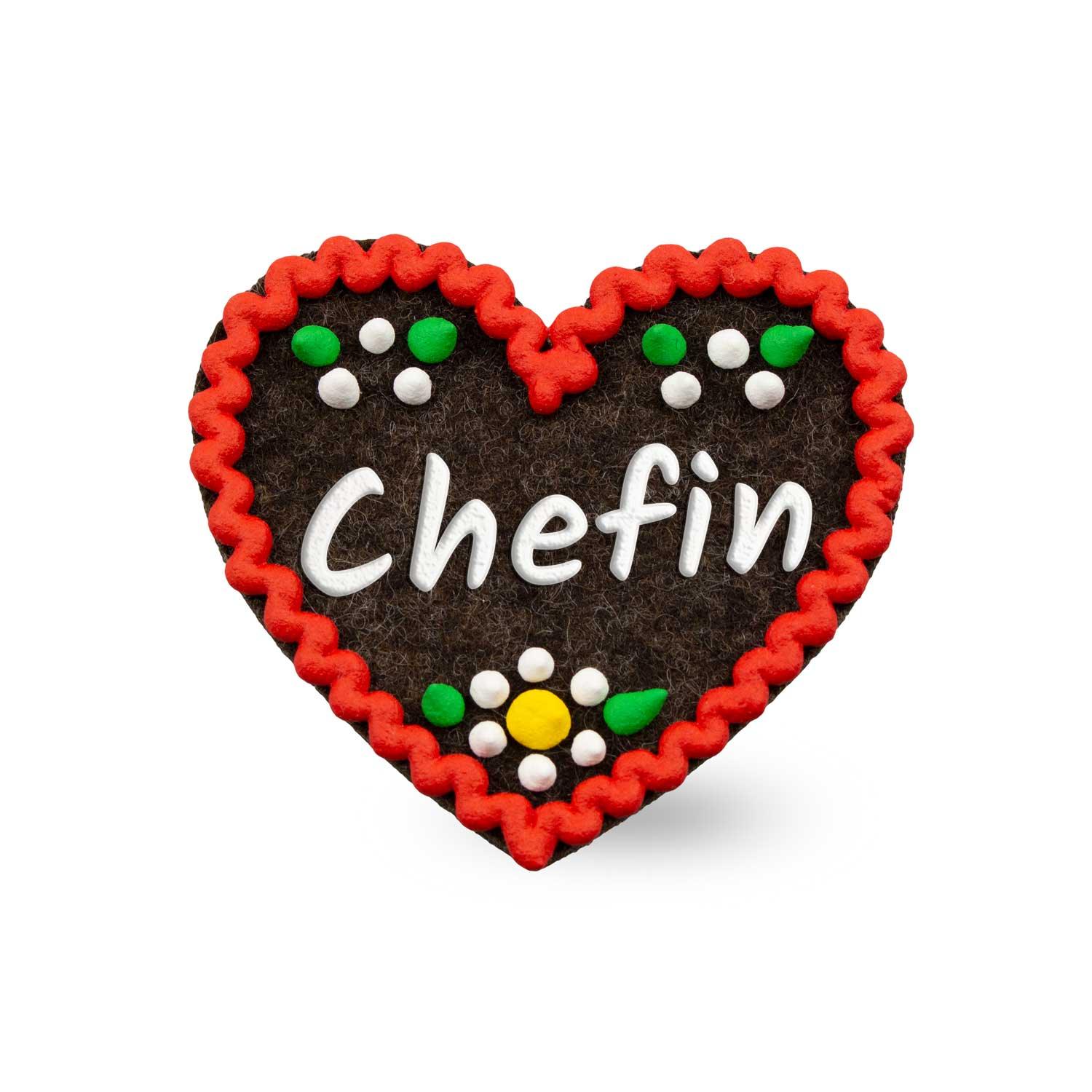 Herzförmiger Filz-Anstecker mit weißem Schriftzug „Chefin“ und Sicherheitsverschluss auf der Rückseite, ca. 6,5 x 7 cm.