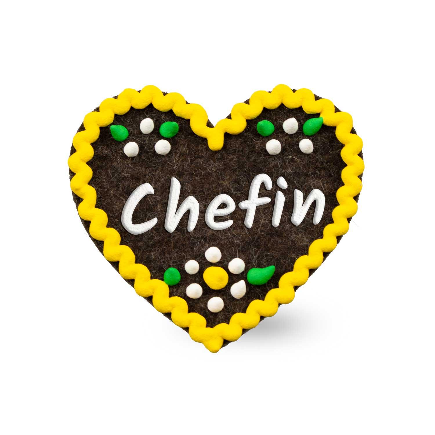 Herzförmiger Filz-Anstecker mit aufgesticktem Schriftzug „Chefin“ und Sicherheitsverschluss auf der Rückseite, ca. 6,5 x 7 cm.