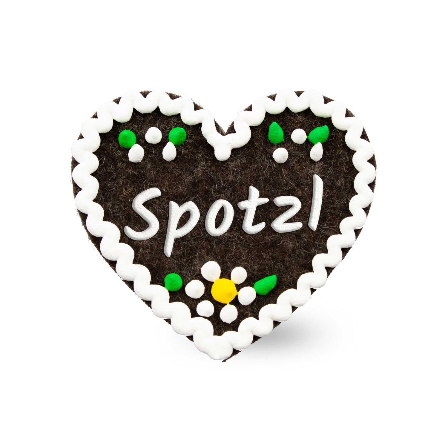 Herzförmiger Filzanstecker mit gesticktem Schriftzug „Spotzl“ und Sicherheitsverschluss auf der Rückseite, ca. 6,5 x 7 cm.